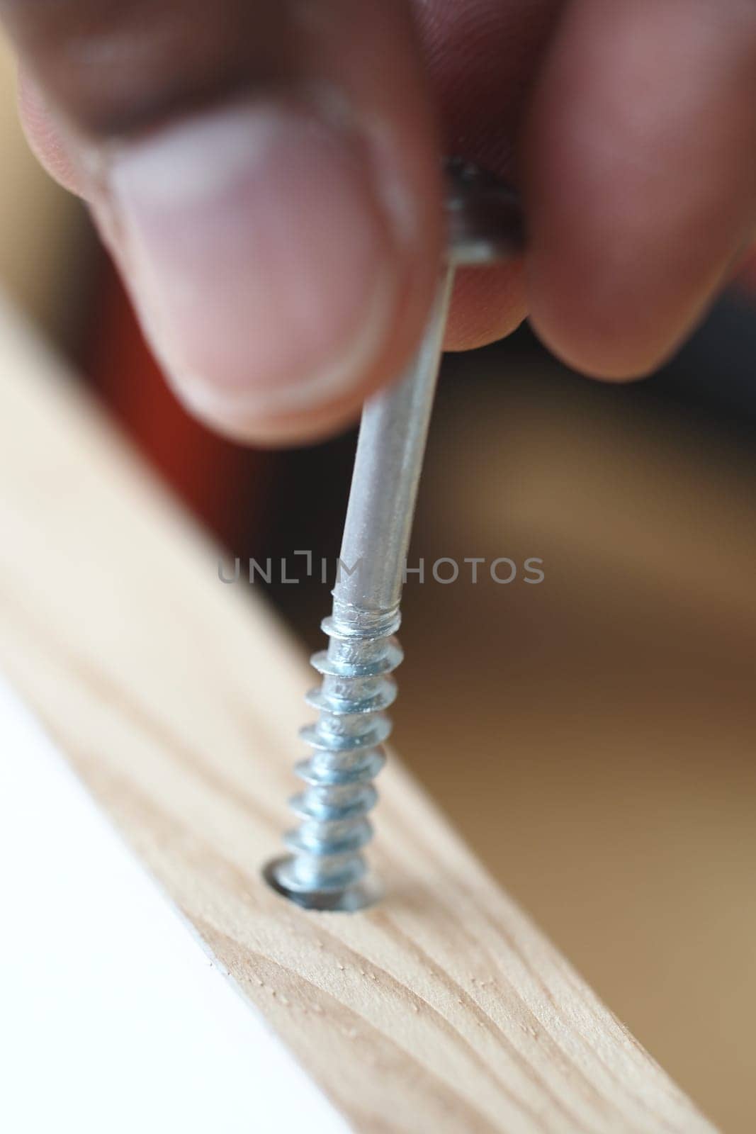 A person firmly secures a screw into wood to enhance stability.