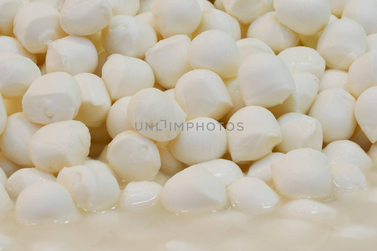 Plump mozzarella balls are arranged neatly in a market stall.