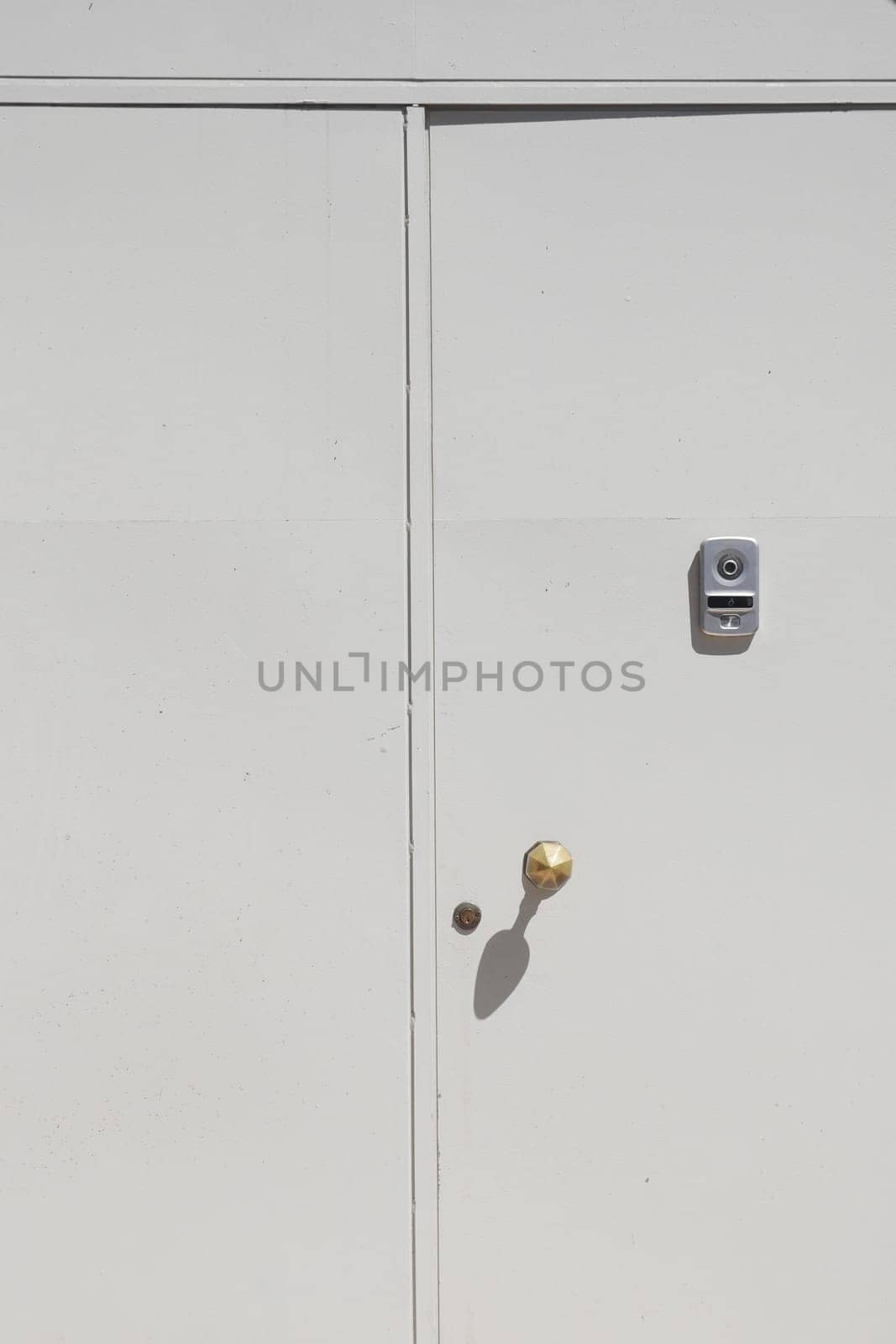A close-up view of a white door showing a brass doorknob and lock.