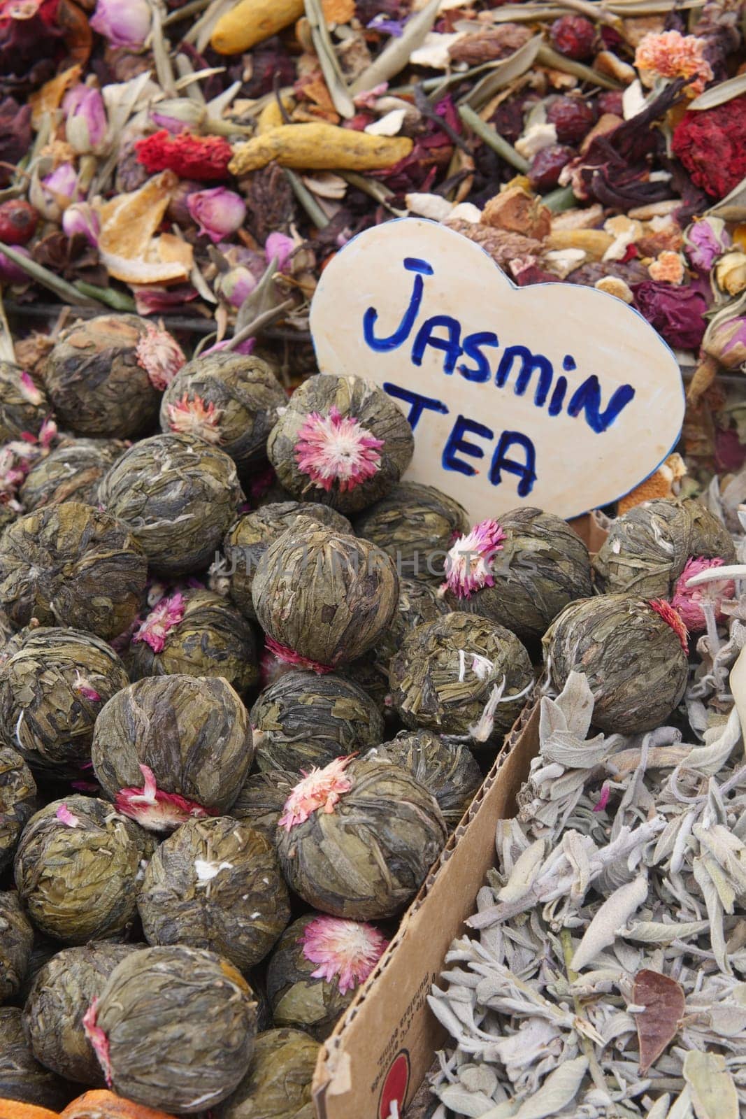 Dried herbs and teas are arranged in colorful piles at a local market.
