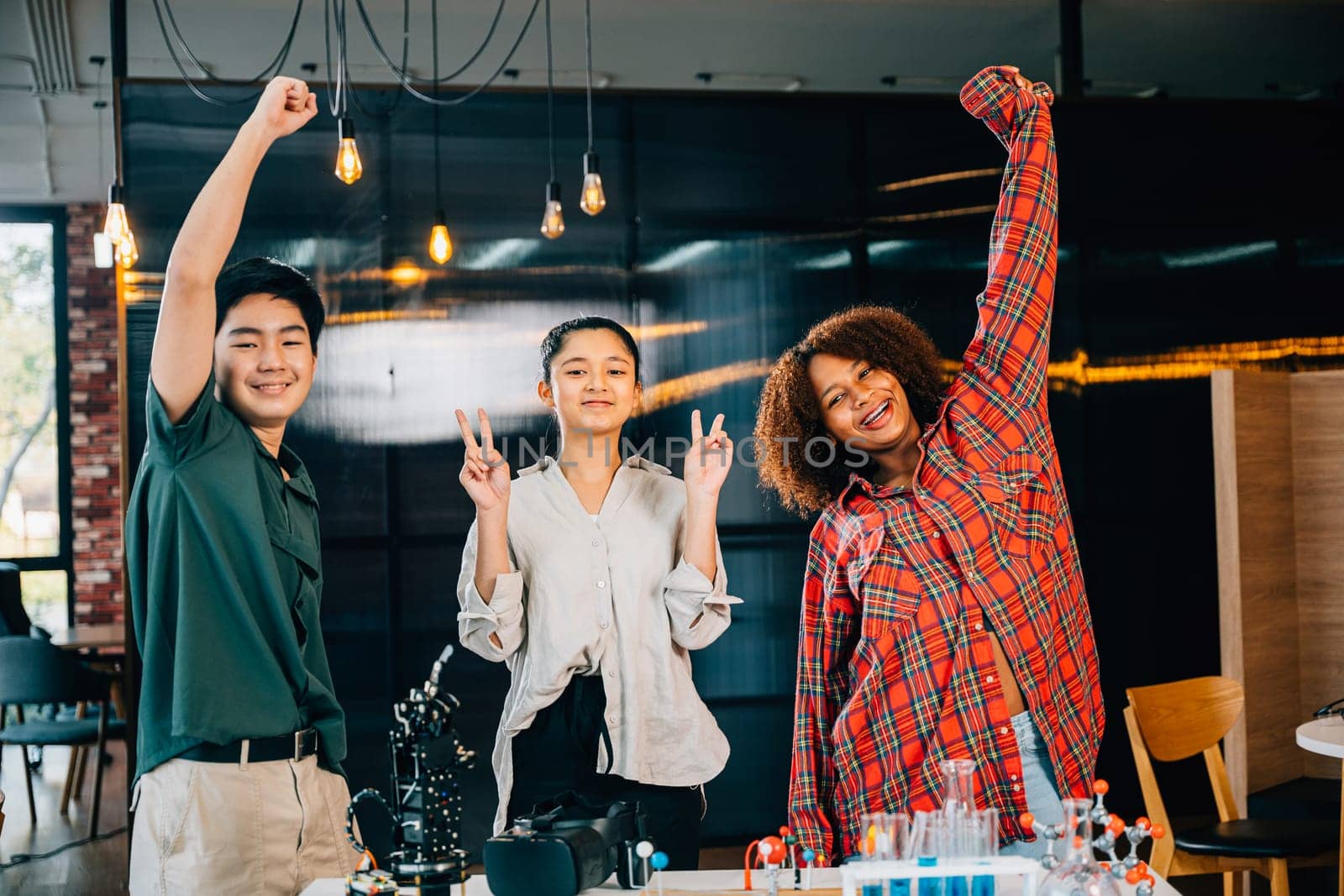 Happy students gathered in classroom excitedly raise hands to celebrate their successful learning in robotics class exploring futuristic robotic arm technology in domain of Innovation and Technology.
