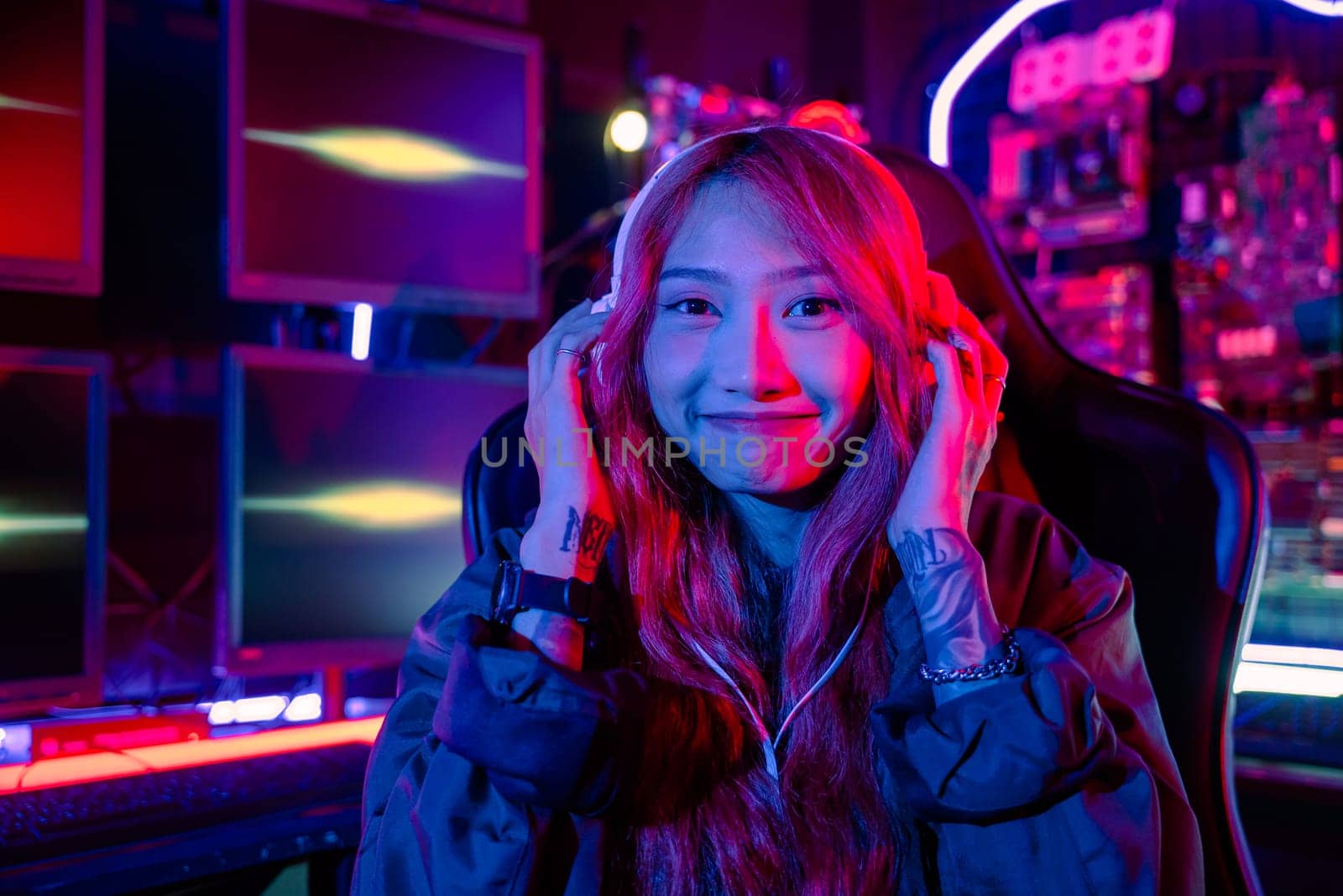 Happy Gamer endeavor plays online video games tournament with computer neon light, Smiling young woman wearing gaming headphones intend to do playing live stream games online at home looking to camera