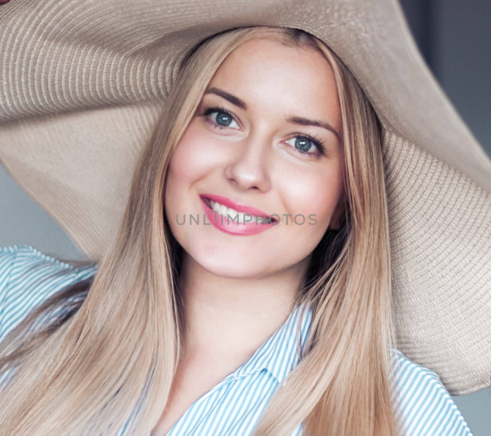 Woman, fashion and summer country charm, blonde beauty and elegance in wide brimmed beach hat. Feminine allure, timeless style and graceful glow. Smile, straw hat and blue striped blouse, natural lighting and effortless charm, fashion look idea