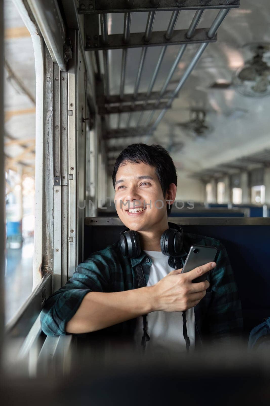 A cheerful traveler on a train, immersed in a phone experience, representing the modern travel lifestyle where technology and adventure go hand in hand.