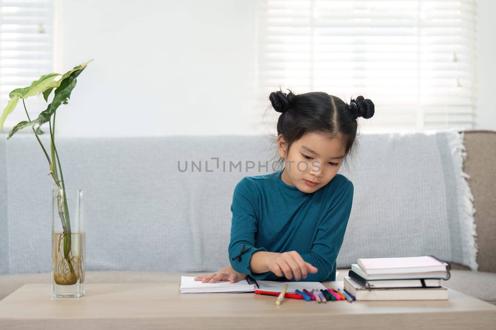 A young girl, deeply focused, is drawing with vibrant colored markers, exploring her creativity in a comfortable home environment. This image highlights childhood imagination.