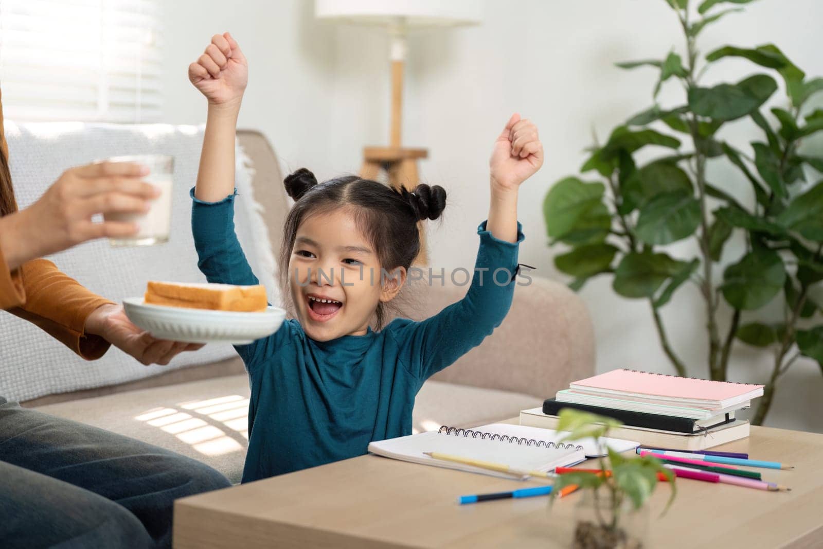This joyful moment shows a girl celebrating snack time while engaging in her studies, emphasizing the balance of fun and learning.
