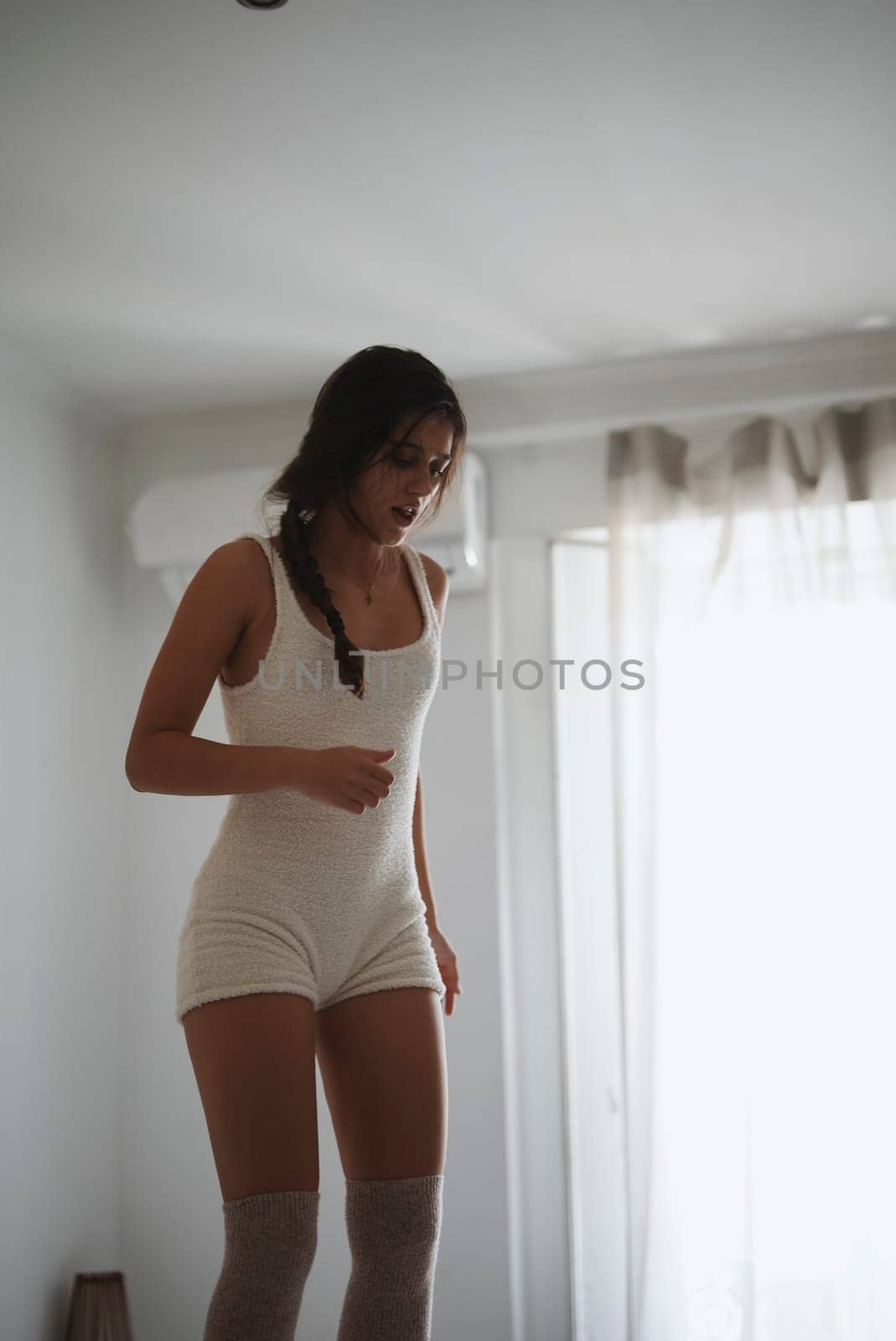 In a beautifully bright and airy room, a young woman gracefully showcases her relaxed yet stylish aesthetic