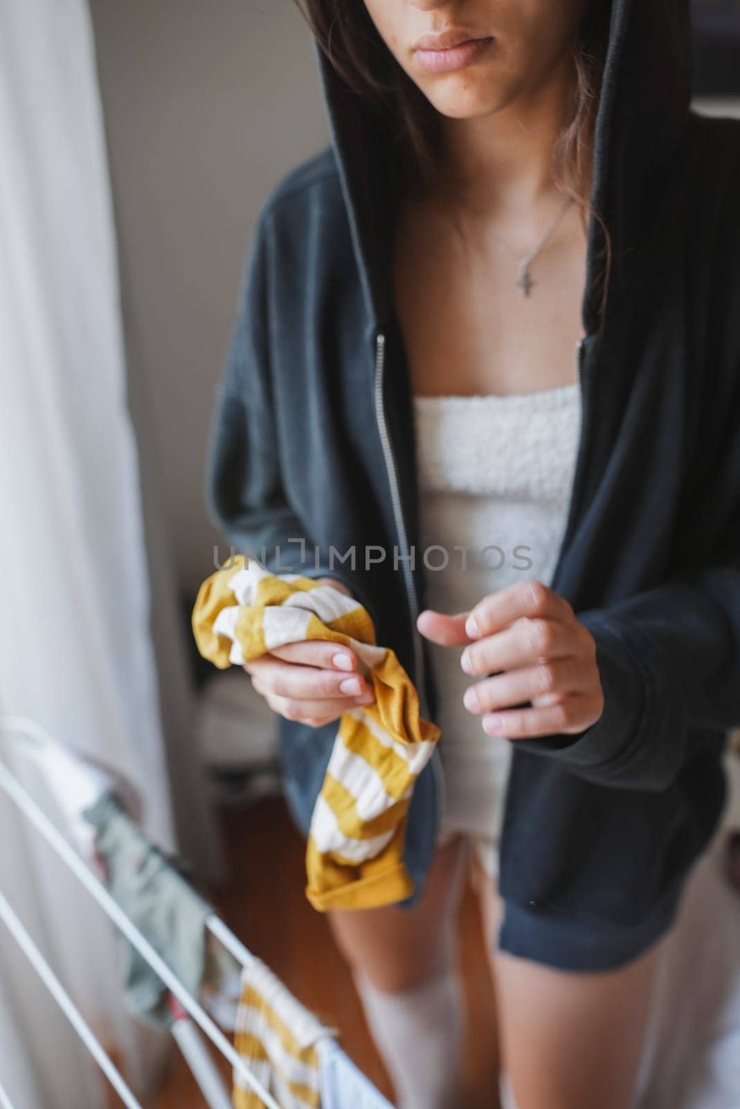 A person dressed casually in a comfy hoodie while holding a colorful cloth, creating a warm and inviting homey vibe