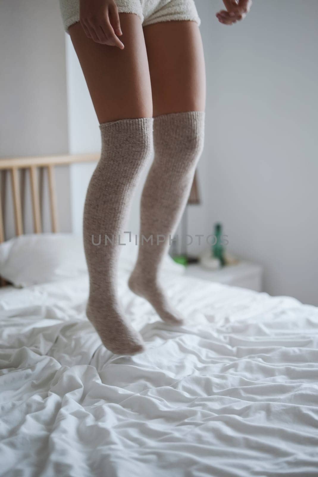 A carefree and joyful moment is captured with legs playfully bouncing in soft kneehigh socks on a cozy bed