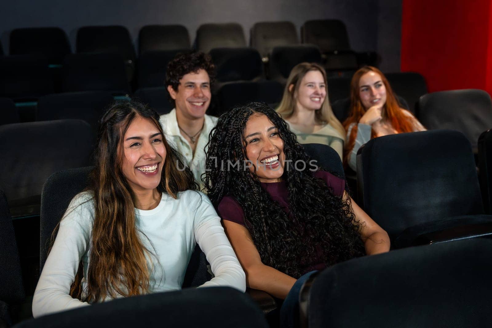 Friends laughing and enjoying a comedy movie at the cinema, sharing joyful moments together in a relaxed and fun atmosphere