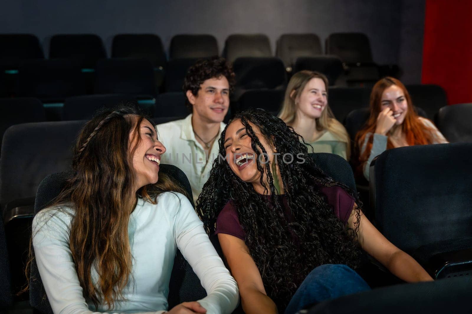 Friends enjoying laughter together while watching a comedy film at the cinema, sharing moments of joy and fun in a vibrant atmosphere