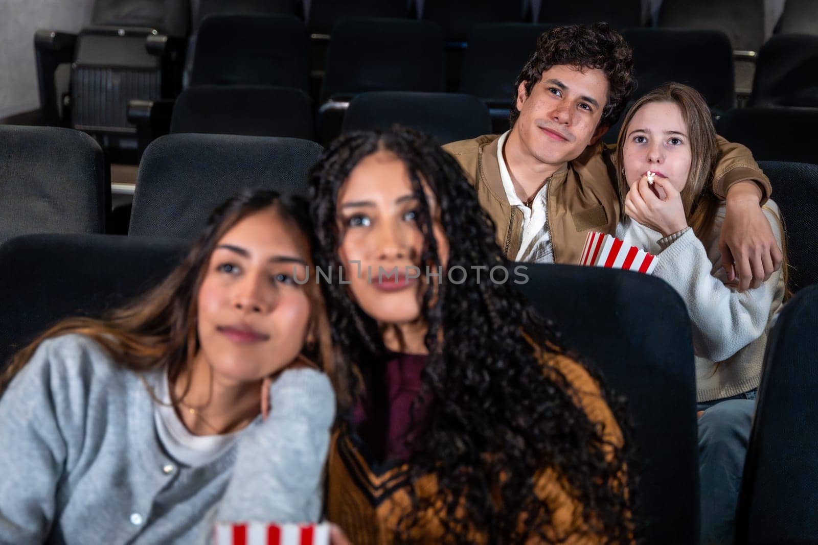Group of friends enjoying a film at the movie theater, sharing popcorn and having fun together