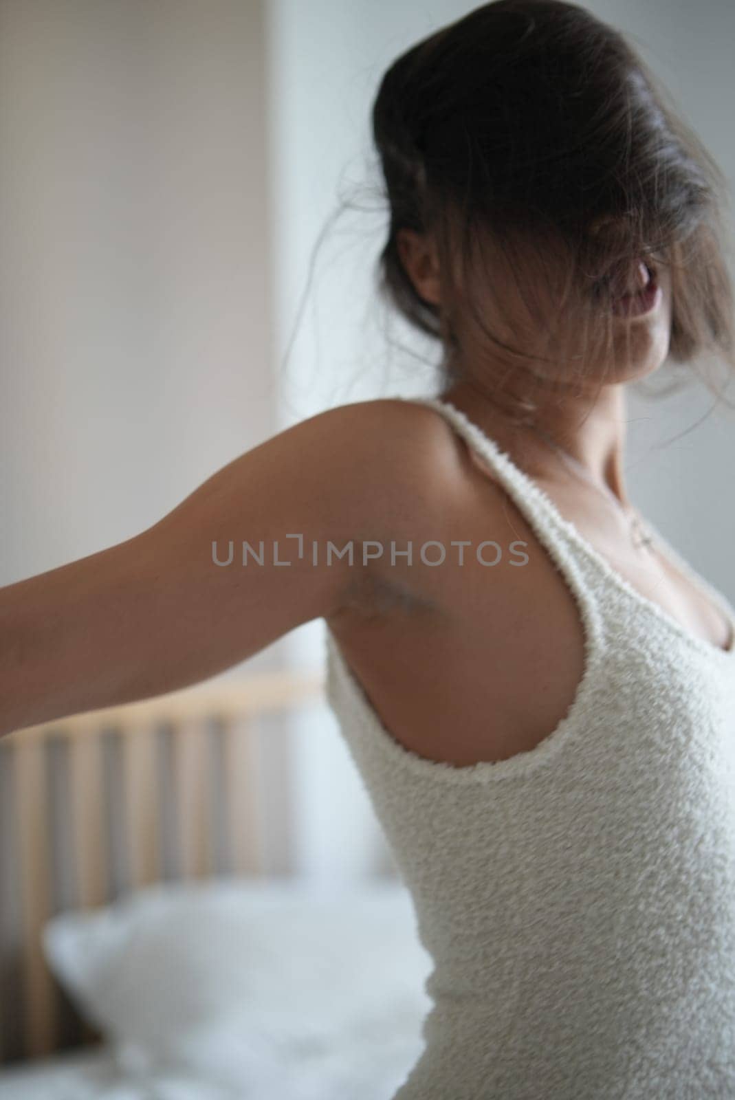 A woman dressed in a soft, comfortable outfit fully embraces the tranquility of a cozy, warm morning setting