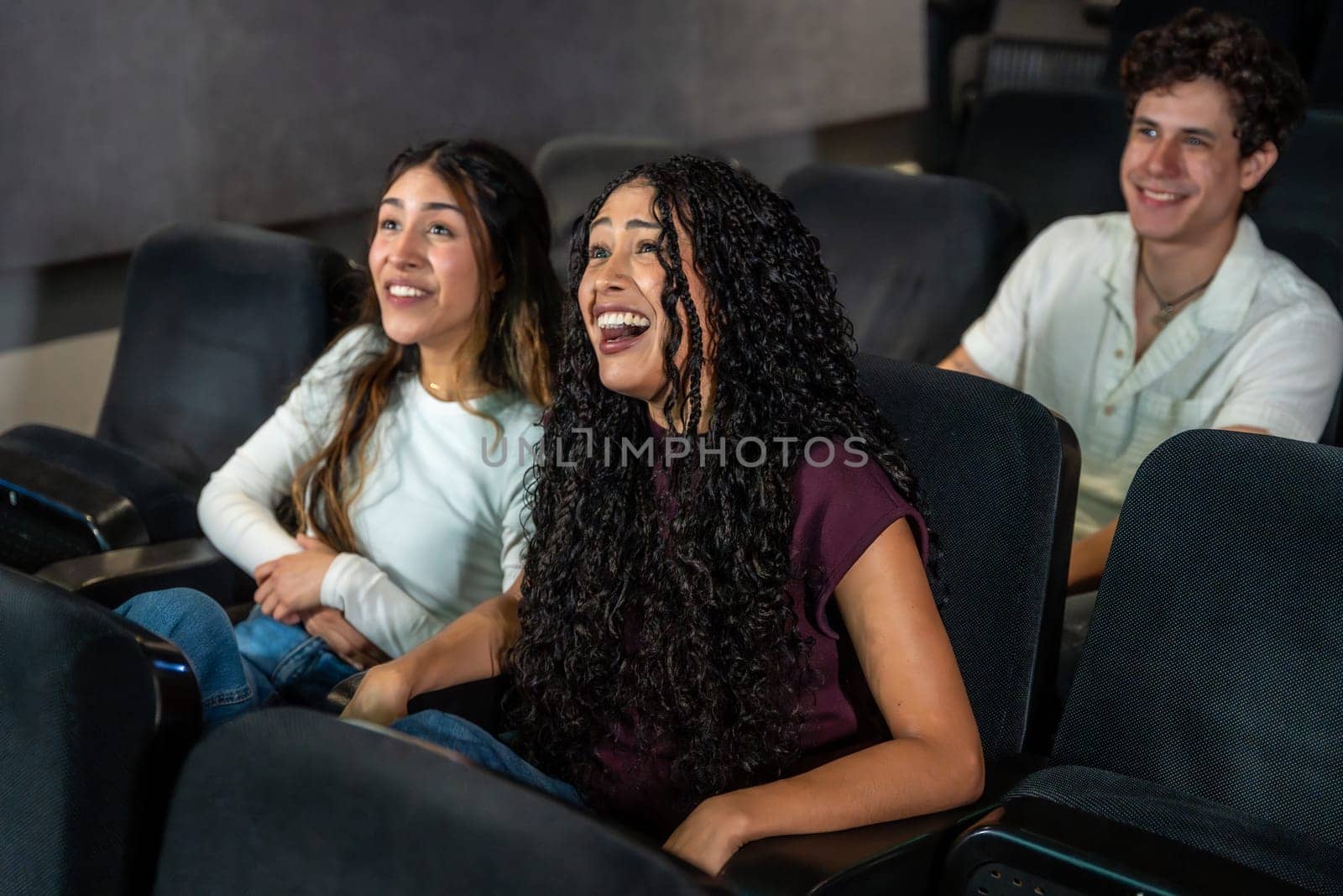 Friends laughing and enjoying a movie at the cinema, sharing a moment of leisure and entertainment