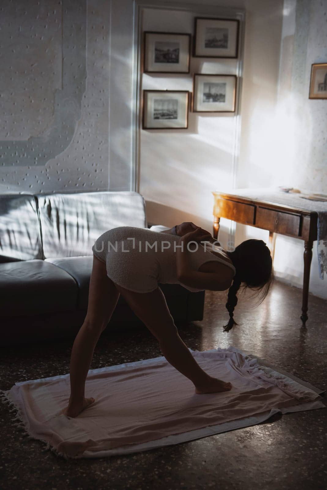 A woman is gracefully practicing yoga in a peaceful living room filled with soft sunlight shining through