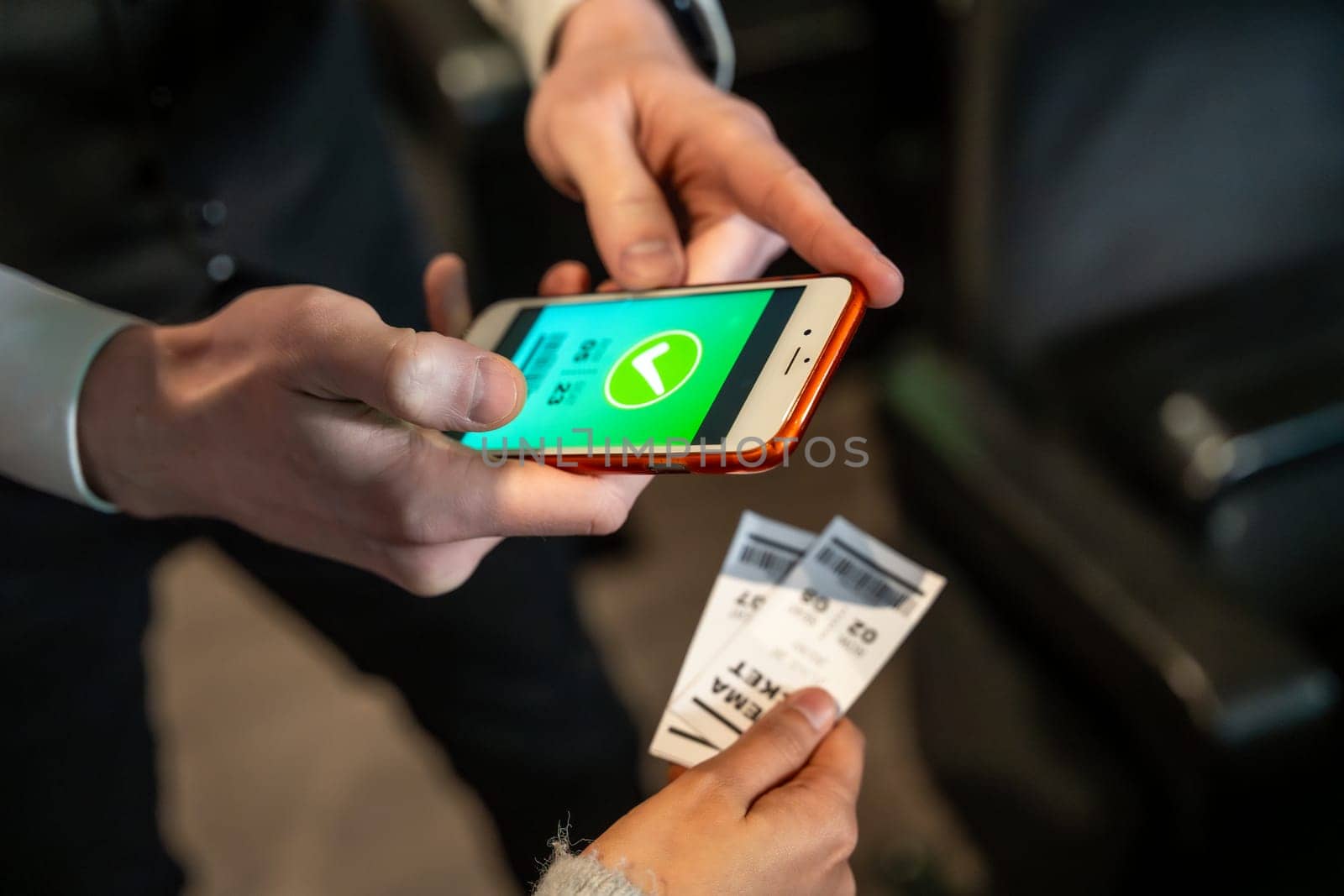 Usher scanning movie tickets on a smartphone from a customer at the cinema entrance, ensuring smooth access and admission to the film