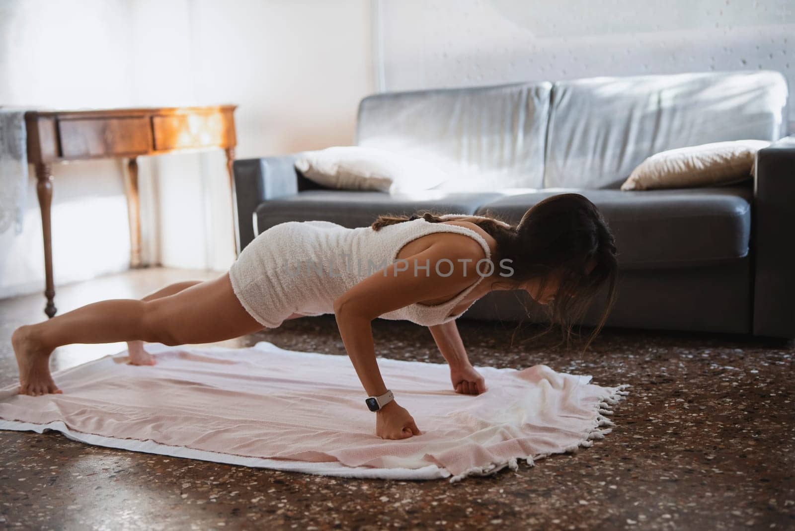 In a cozy indoor environment, a woman is performing pushups on a mat, promoting overall fitness and wellness