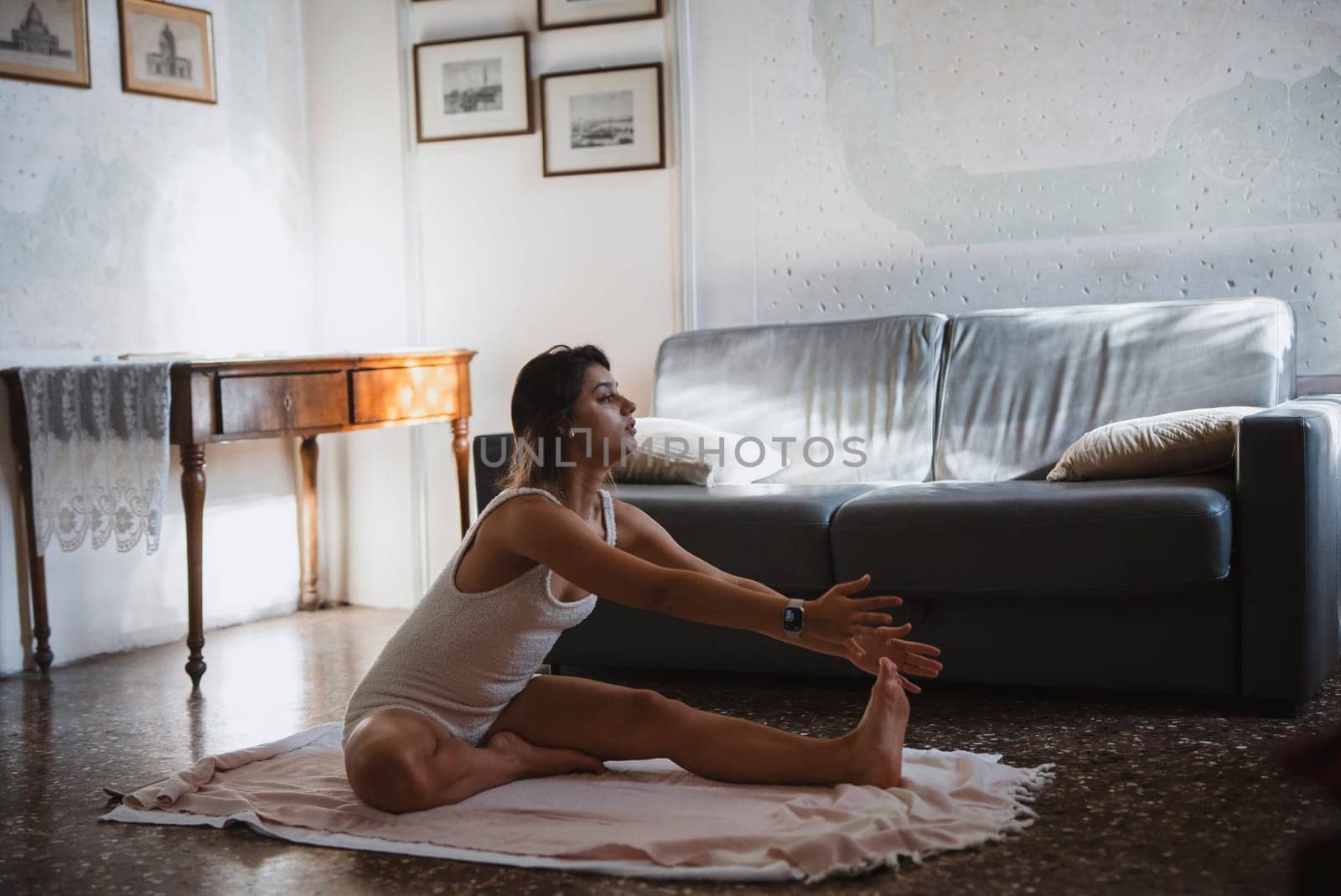 A woman gracefully practices various yoga stretches in her cozy living room, promoting overall wellness and relaxation