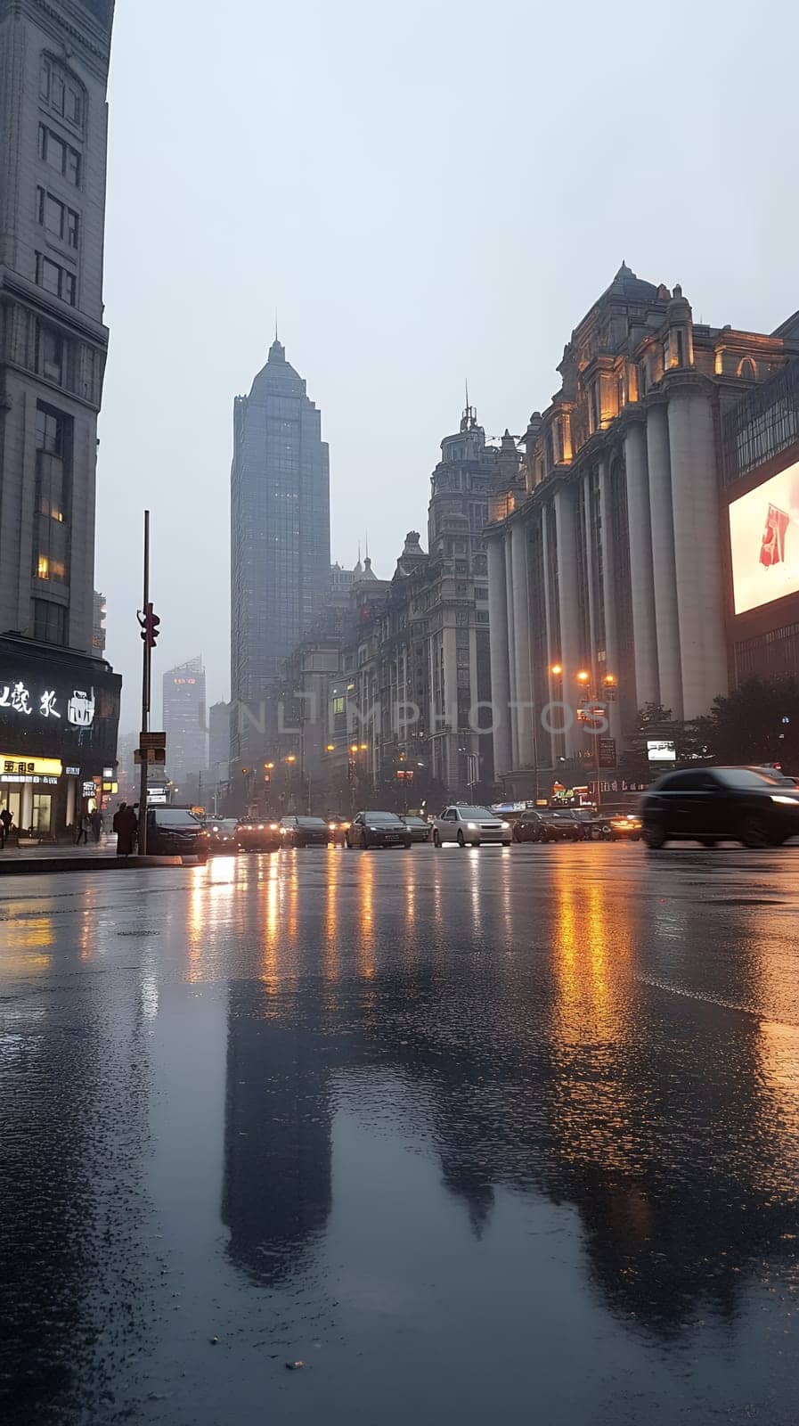 A bustling city street at dusk with wet pavement reflecting the city lights, creating a vibrant urban scene.