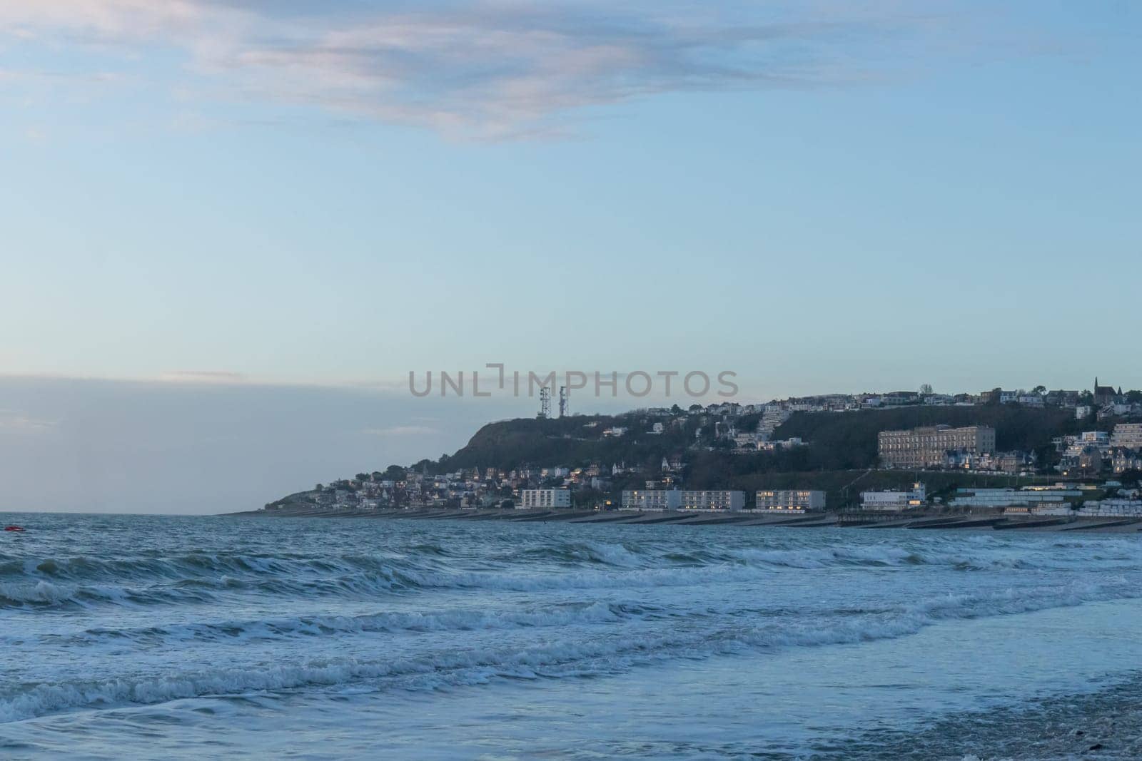Le Havre, France, February 26, 2025: The high cliffs of Normandy rise above the sea in Le Havre, glowing with the last light of sunset as twilight wraps the coastline in soft, fading colors