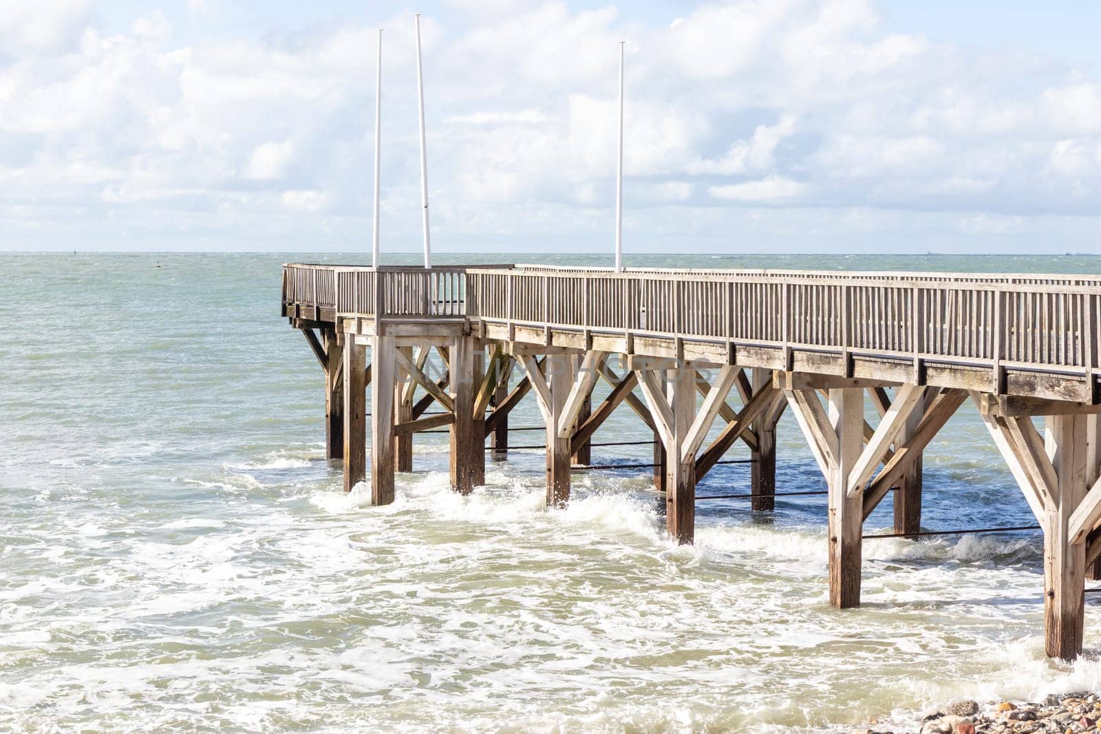 Sainte-Adresse, France - February 27, 2025: A wooden pontoon stretches into the English Channel from Sainte-Adresse, near Le Havre, under a cool February sky along the coast of Seine-Maritime, France