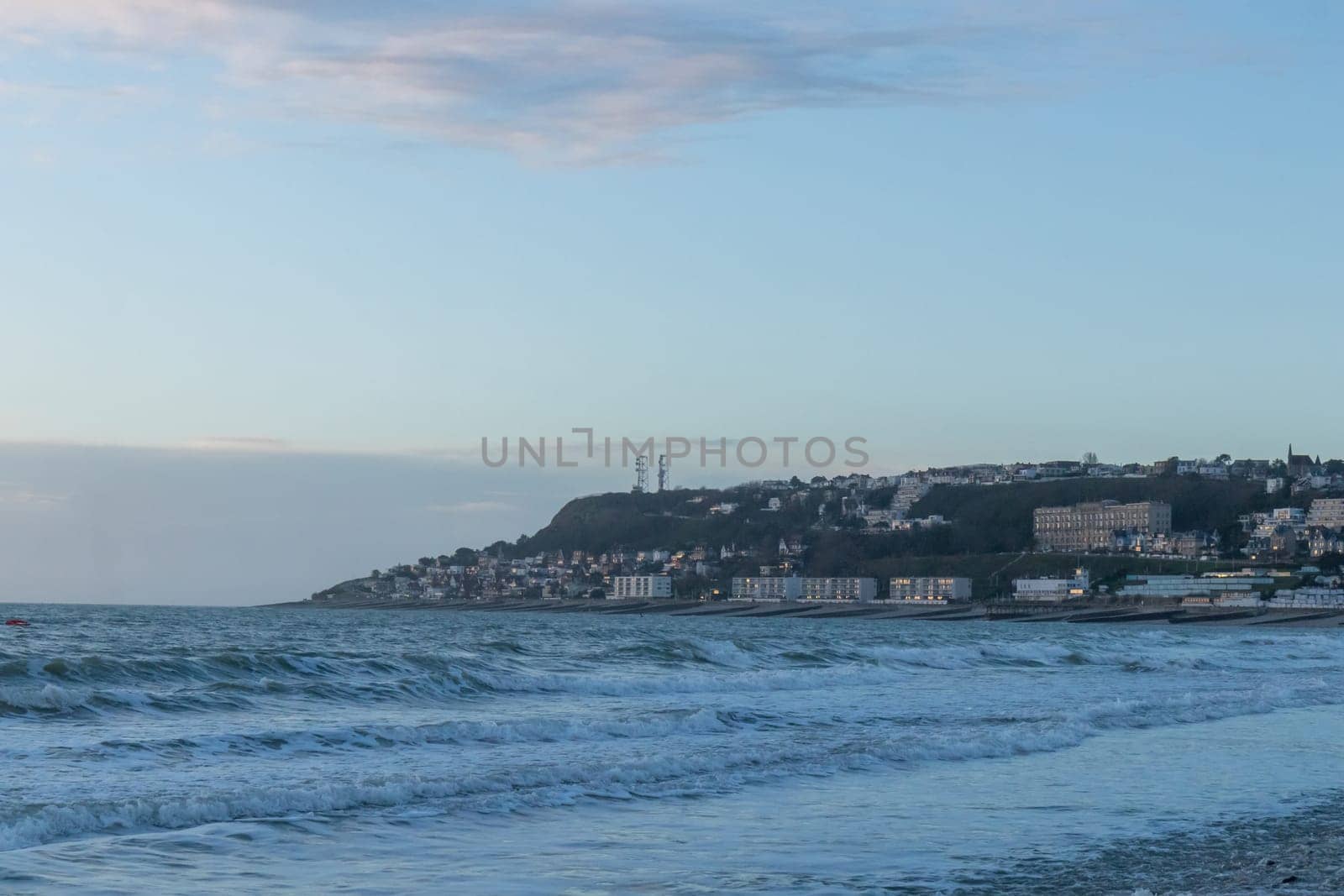 Le Havre, France, February 26, 2025: The high cliffs of Normandy rise above the sea in Le Havre, glowing with the last light of sunset as twilight wraps the coastline in soft, fading colors