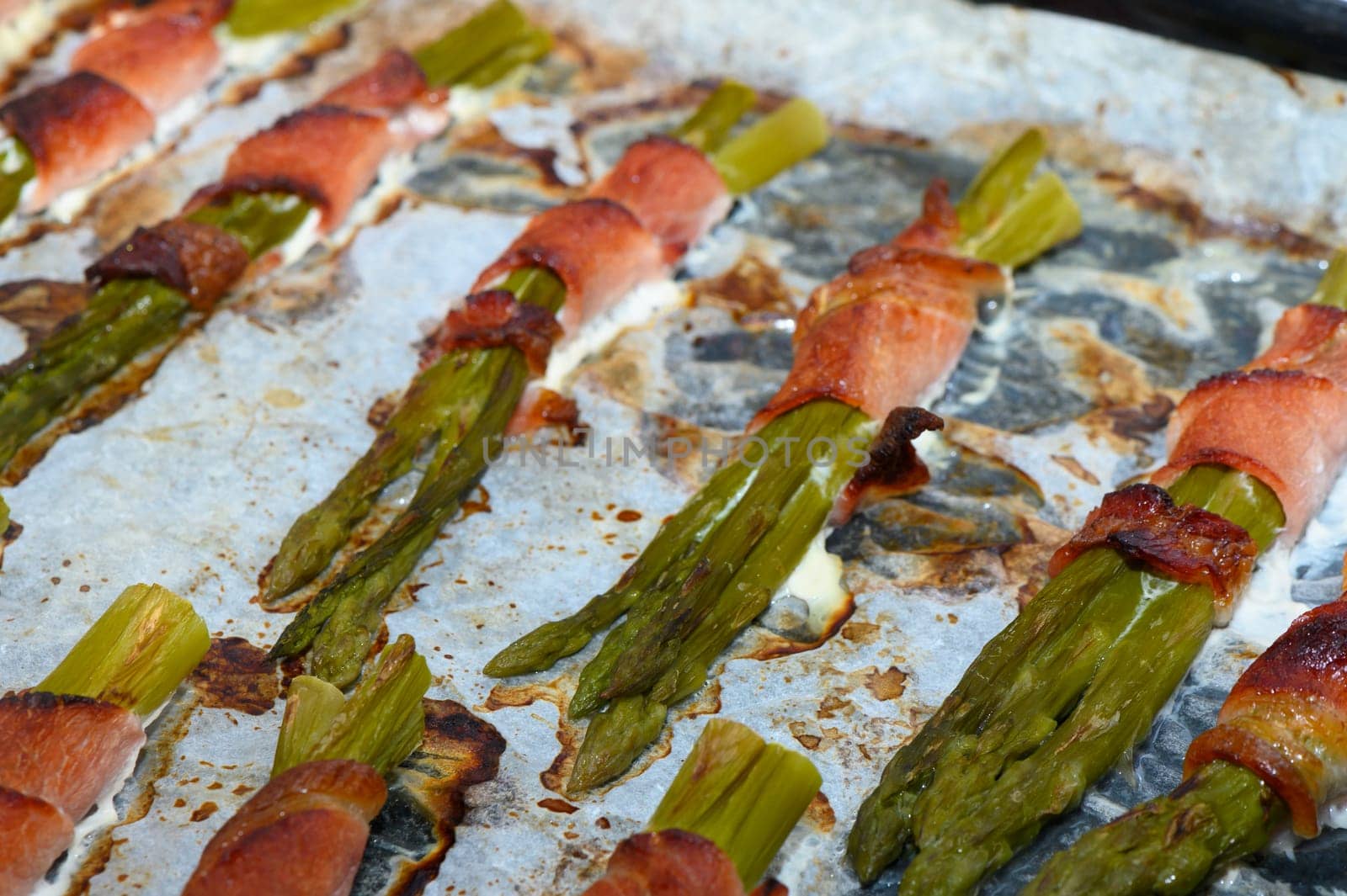 Fresh asparagus spears are beautifully wrapped in crispy bacon, sizzling with flavor on a baking sheet. This barbecue delight is perfect for outdoor gatherings, blending savory and fresh tastes.