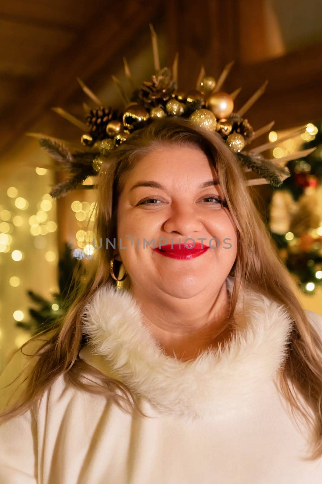 A woman with long blonde hair wears a white fur coat and a crown of golden ornaments. She smiles at the camera.