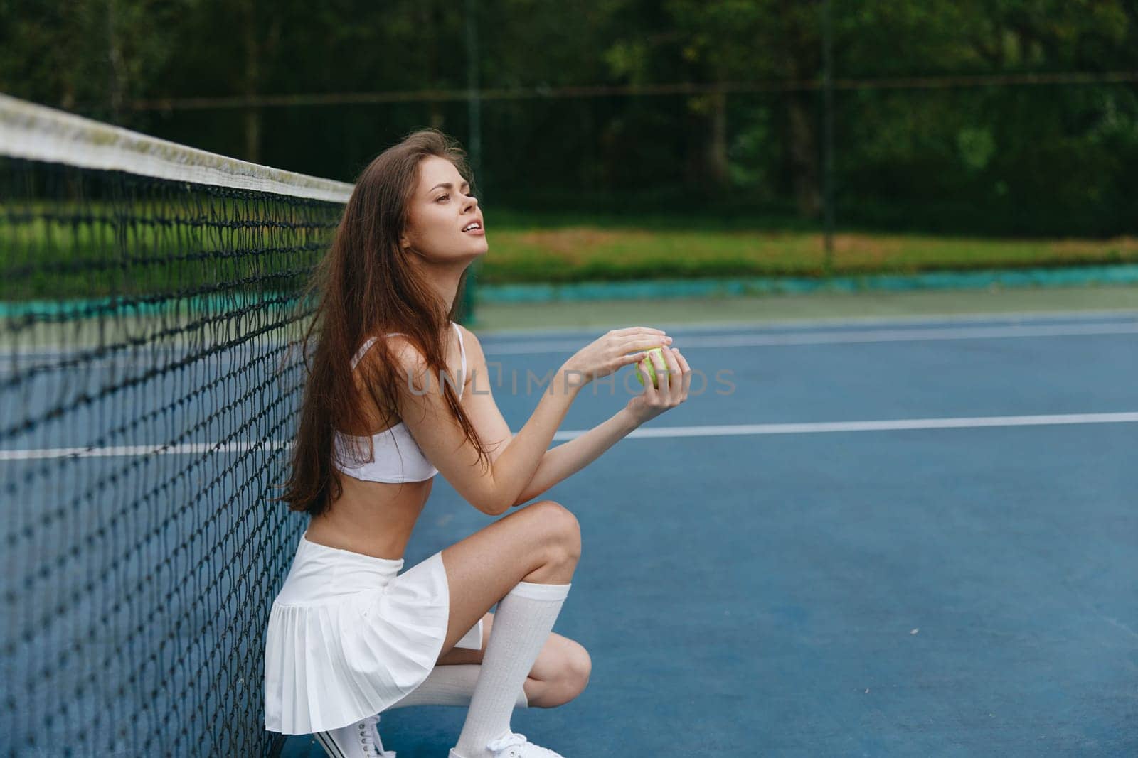 Female tennis player wearing a sporty outfit poses on a tennis court, showcasing concentration and determination with a vibrant background reflecting a seasonal sports lifestyle