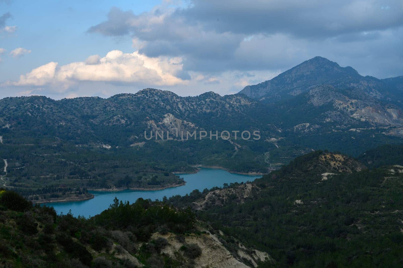 A breathtaking panorama captures a tranquil lake nestled among majestic mountains, reflecting the soft hues of the twilight sky, hinting at the day's end and nature's beauty.