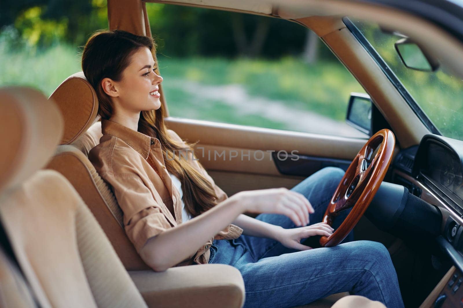 Joyful young woman enjoying a drive in a vintage car, capturing the essence of freedom and adventure in a natural green setting, ideal for travel and lifestyle concepts.