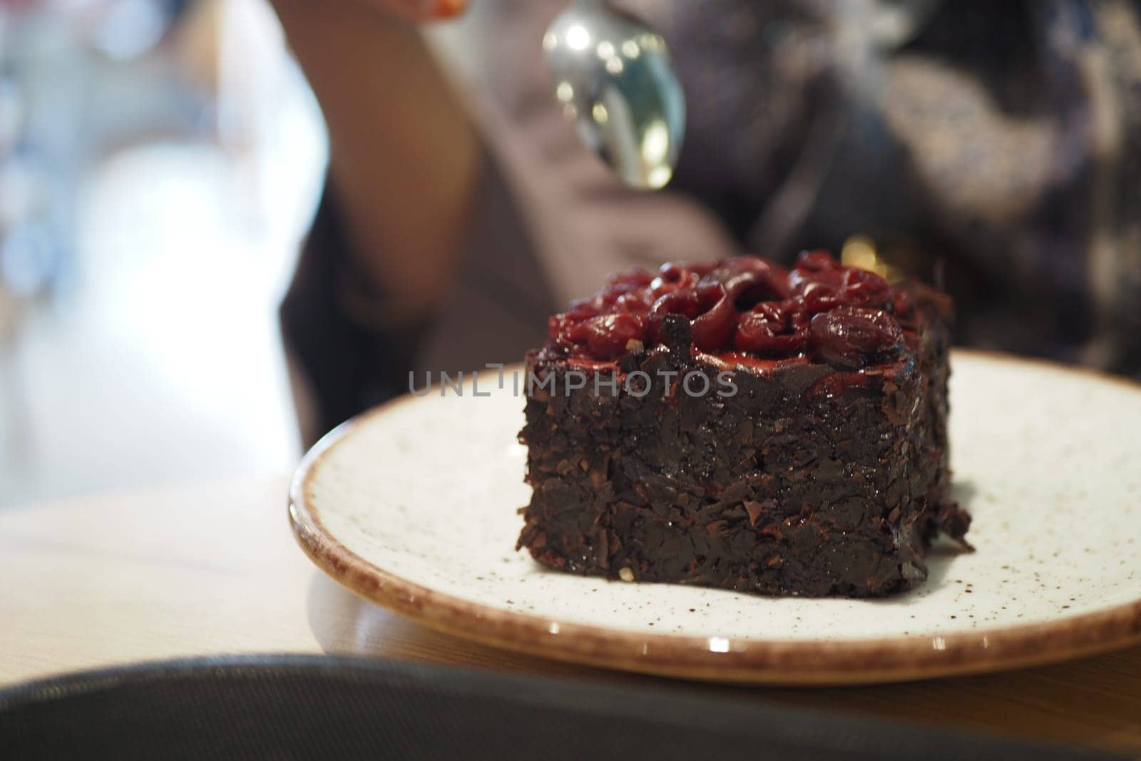 A rich chocolate cake topped with cherries is ready to be enjoyed.