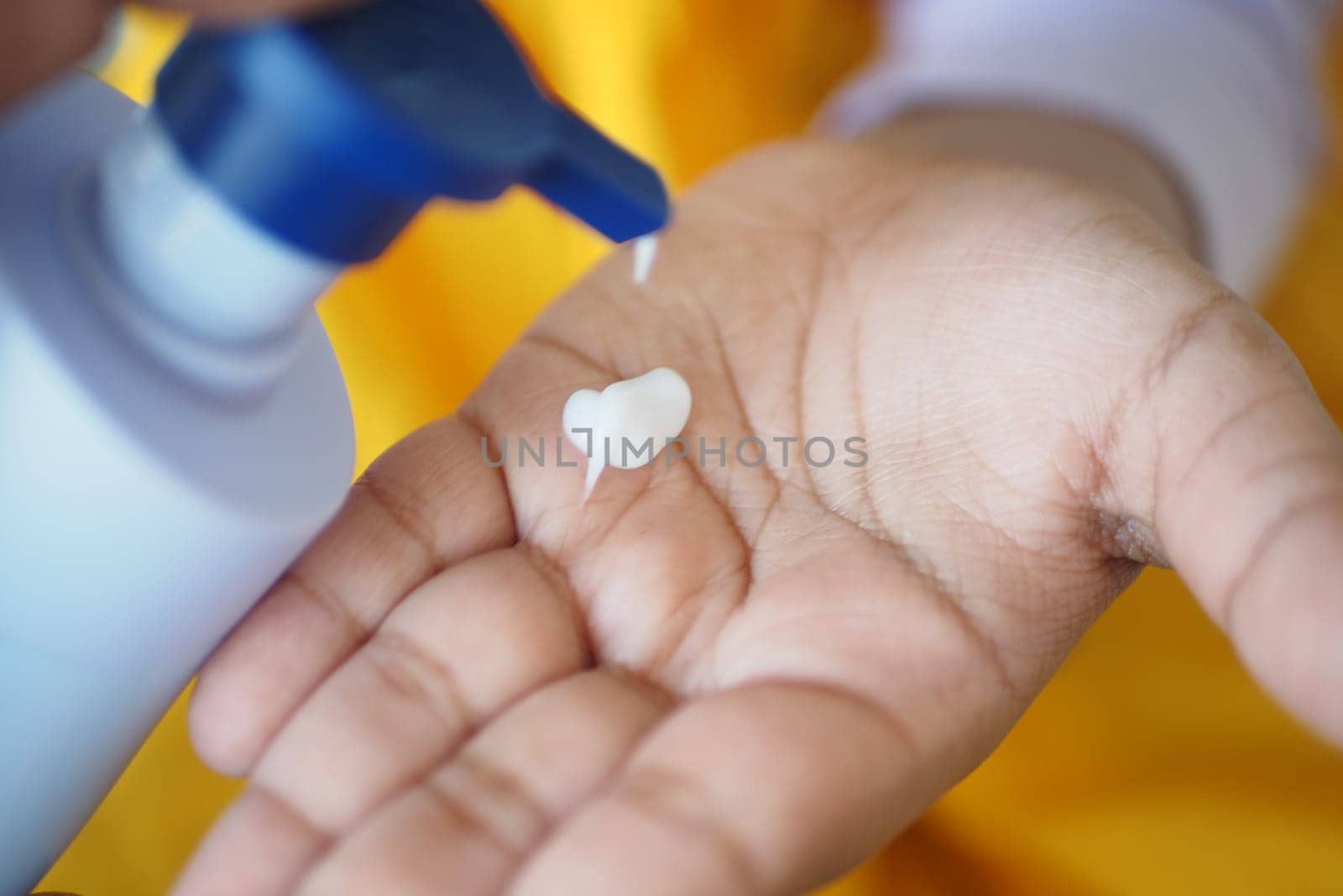 Hand holds lotion with a small amount dispensed for moisture application.