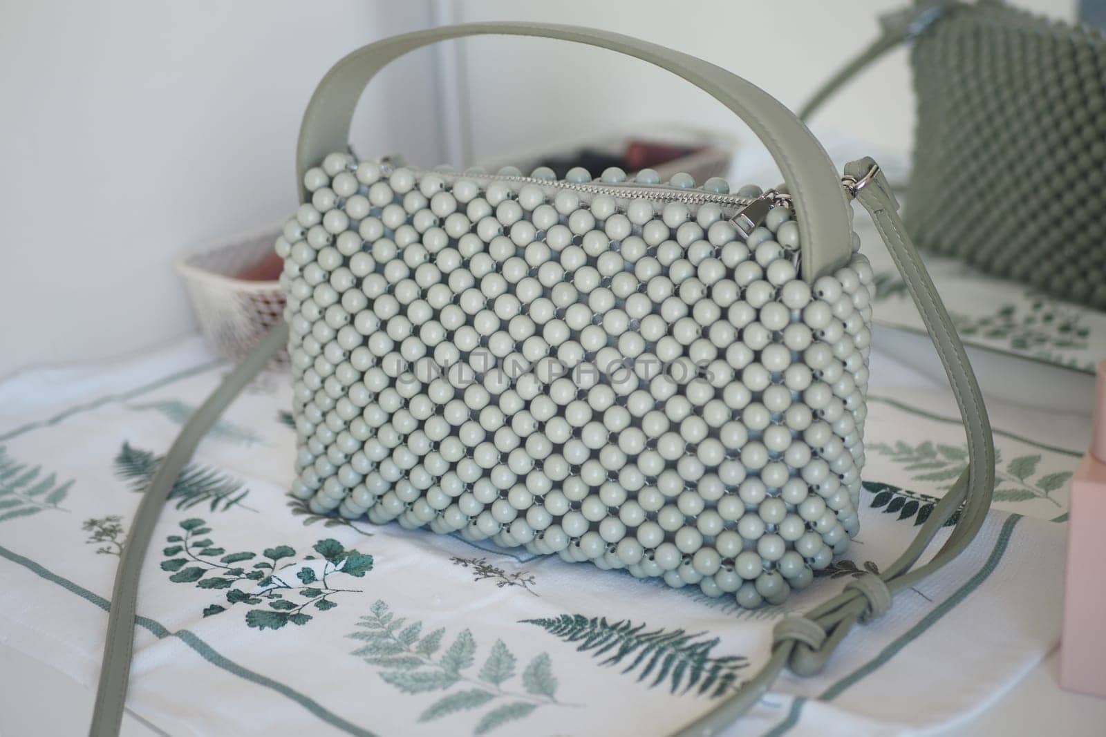 Unique green handbag featuring textured bead design on a table.