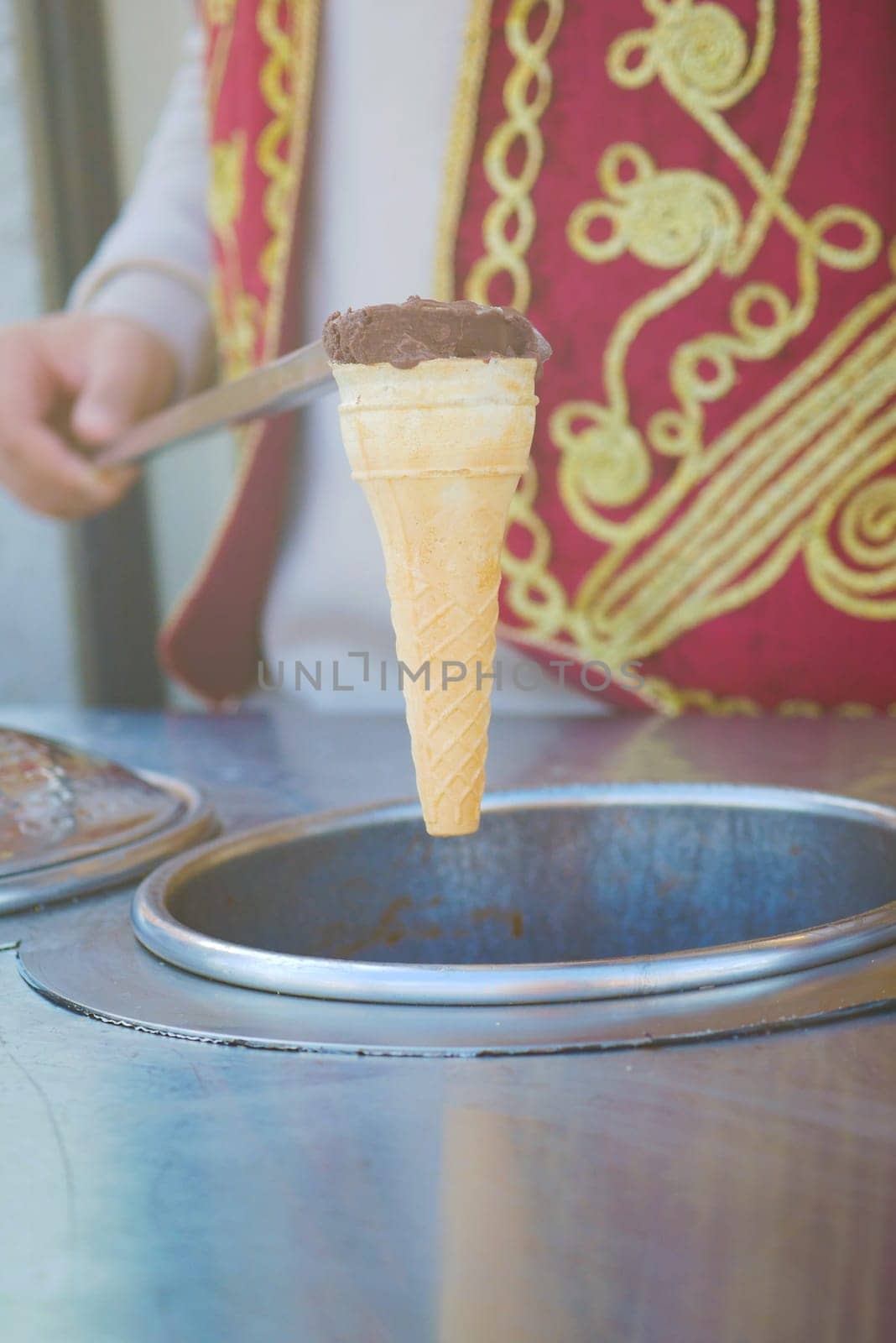 A vendor hands over a delicious ice cream cone topped with chocolate.