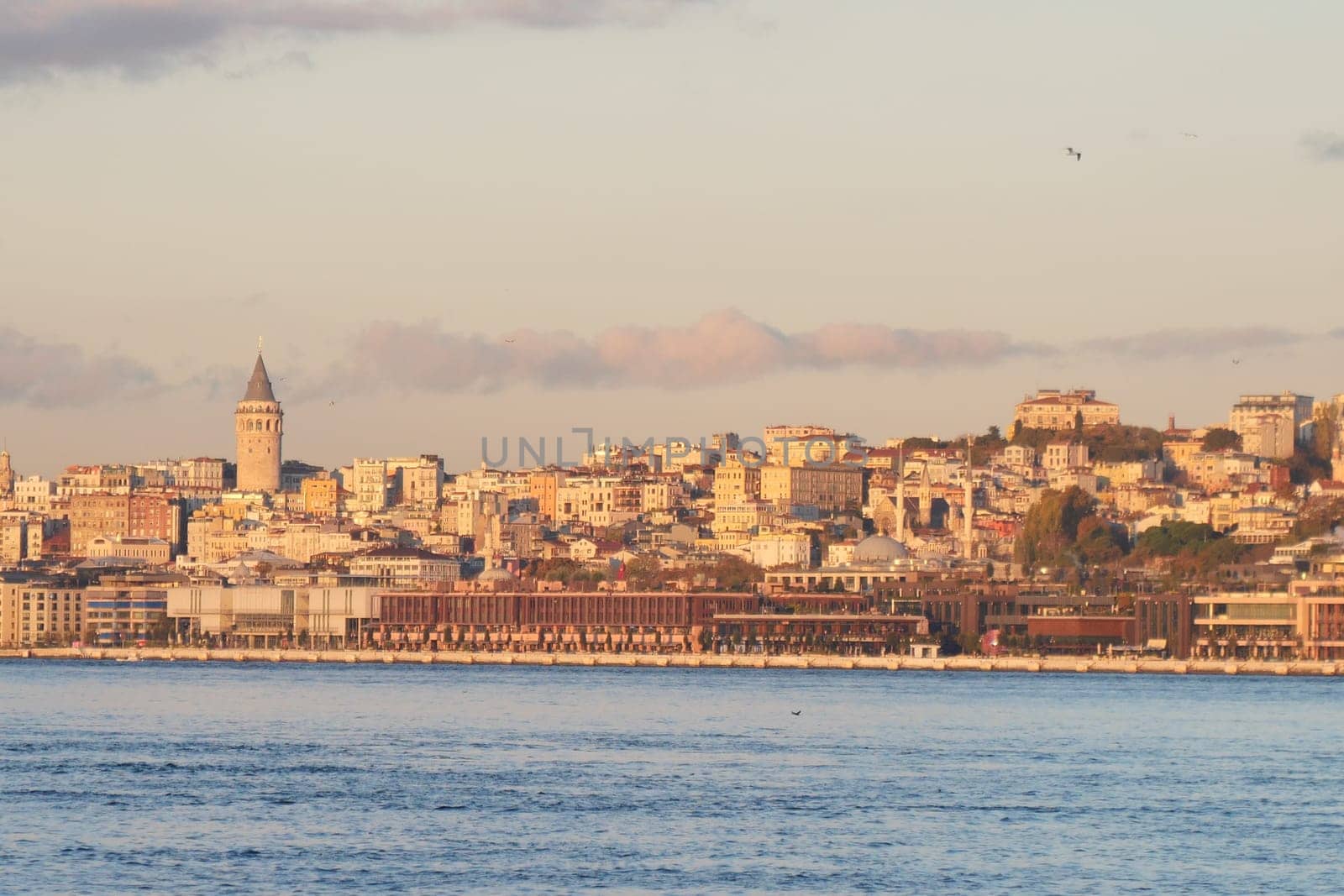 Istanbul's skyline displays historic buildings along the waterfront at sunset.