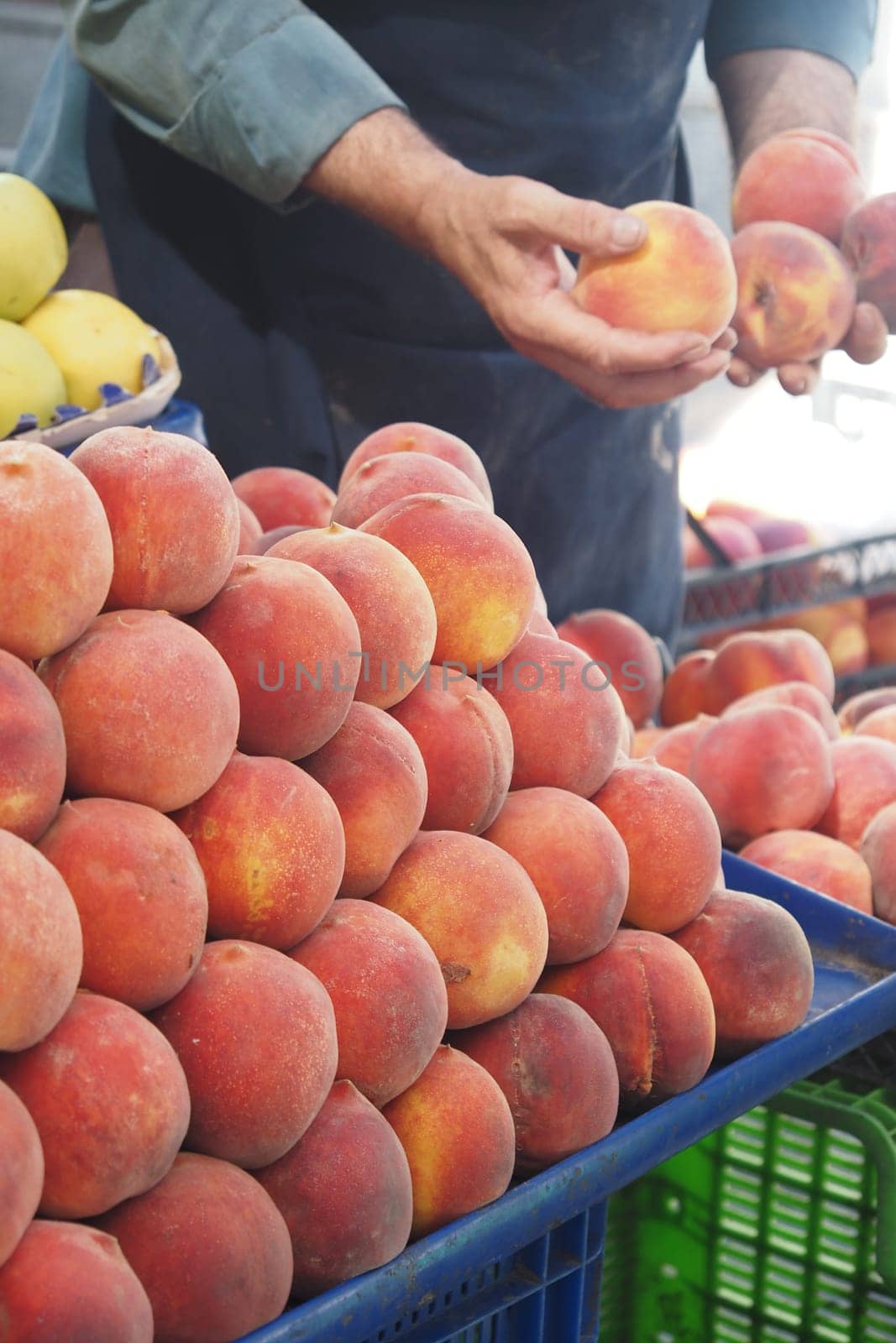 A vendor sorts through fresh peaches at a bustling market stall.