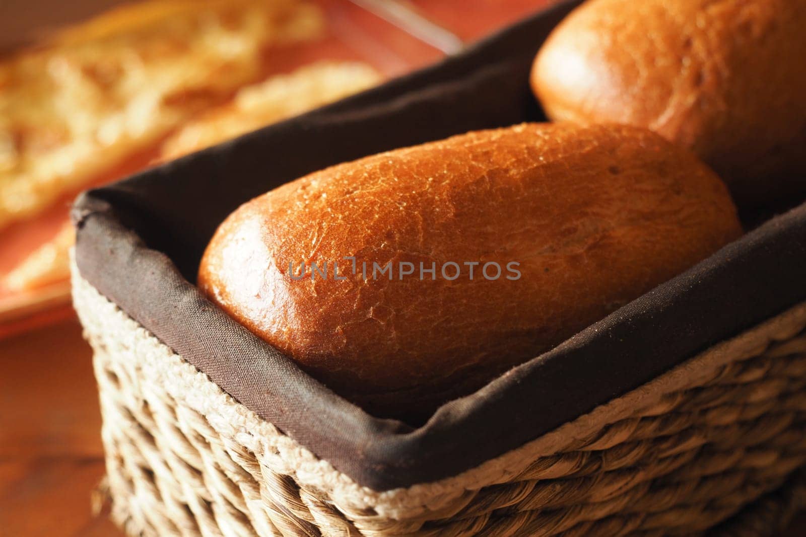 Two golden-brown bread rolls rest in a woven basket, invitingly fresh.