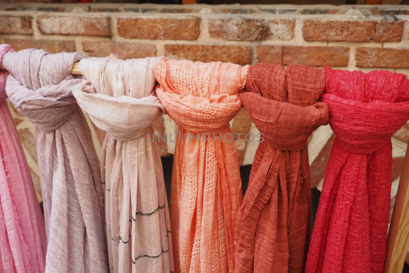 Rows of vibrant scarves display various textures and hues in a market.
