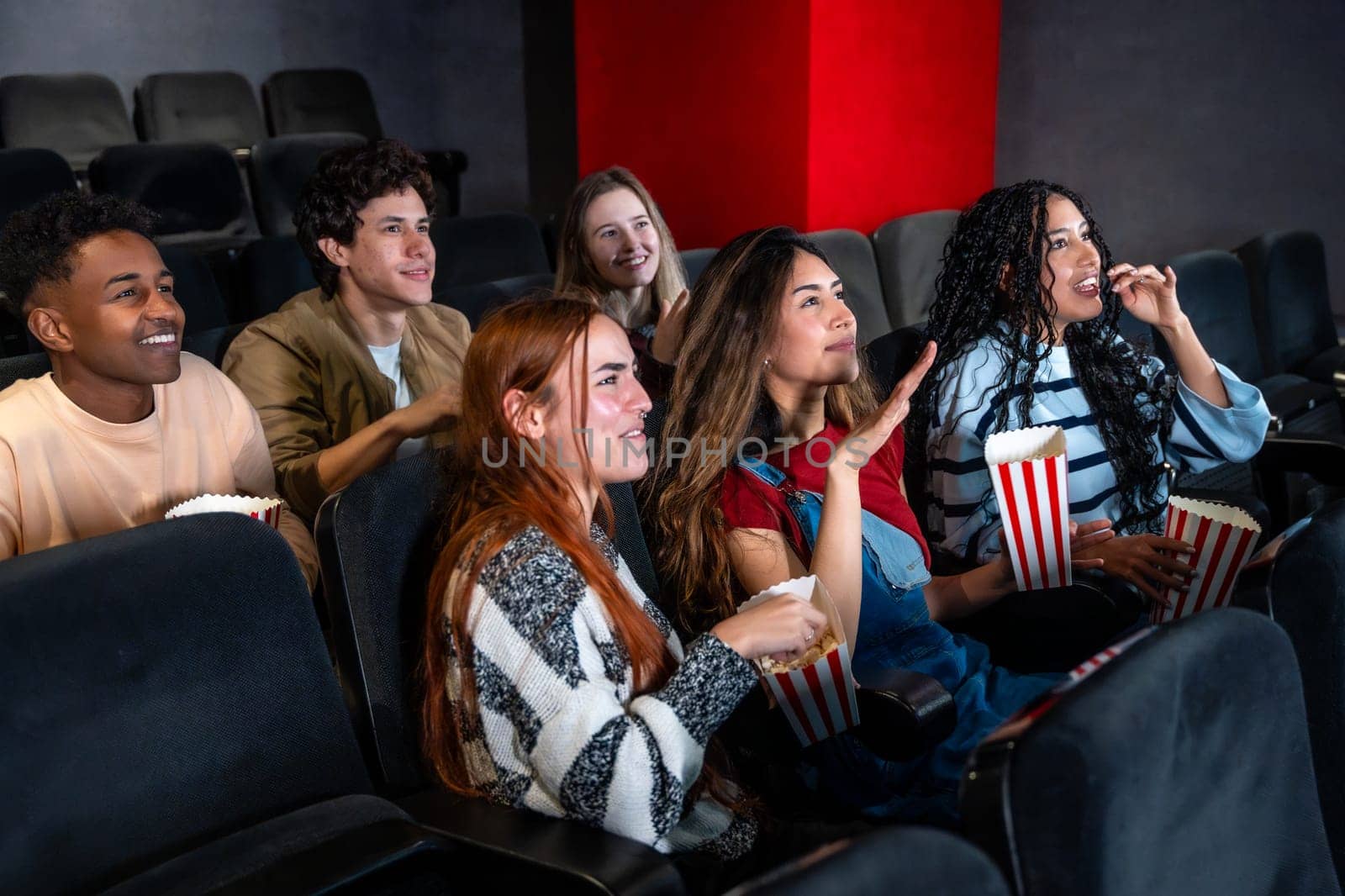 Friends enjoying a film in a movie theater, munching on popcorn and sharing laughter, creating joyful memories together