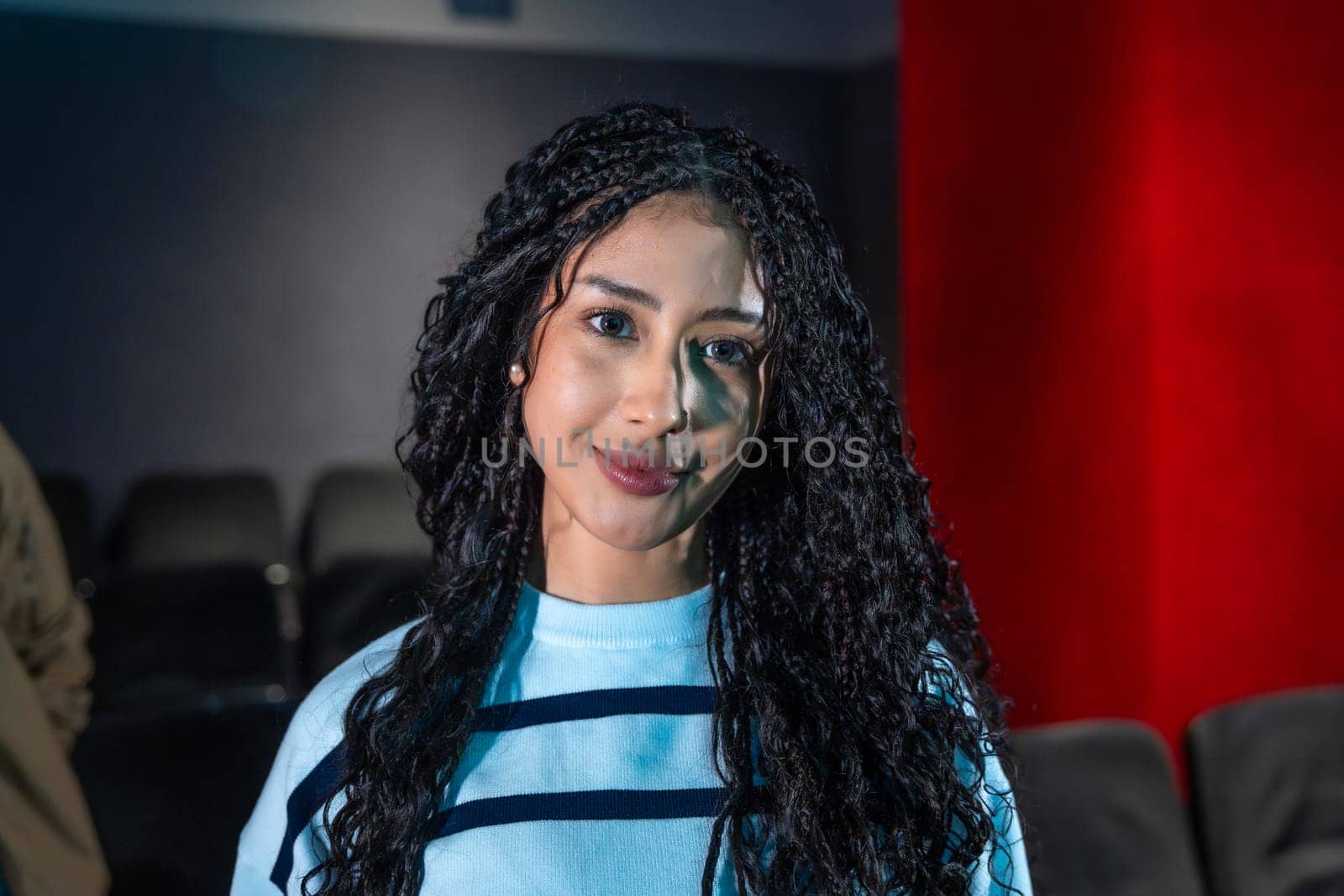 Young woman smiling during a movie session, premiere, or special event, enjoying the atmosphere of cinema or disco