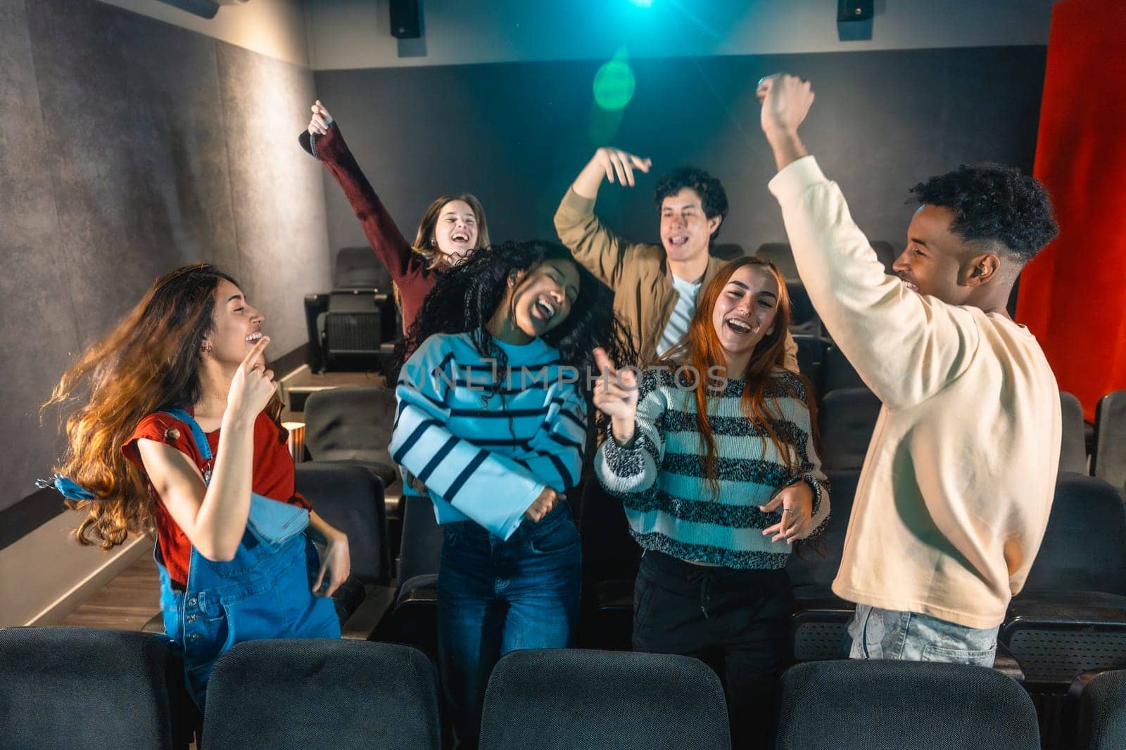 Cheerful multi ethnic friends dancing and enjoying music during movie disco event in cinema theater