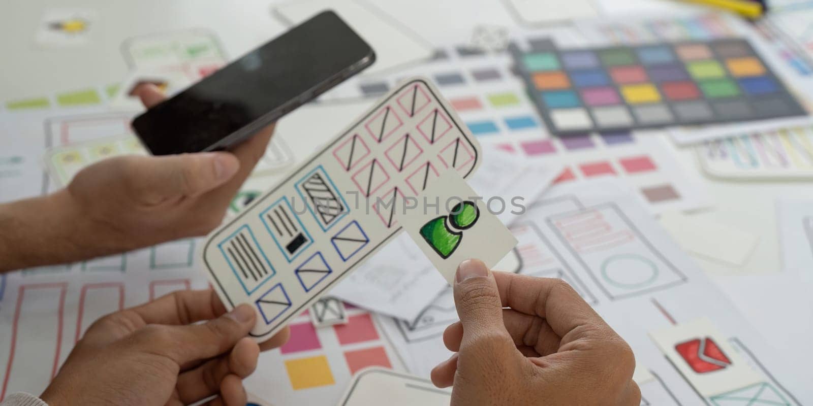 A team is engaged in a creative session, discussing mobile app designs and wireframes while using sketches to visualize ideas and collaborate effectively.