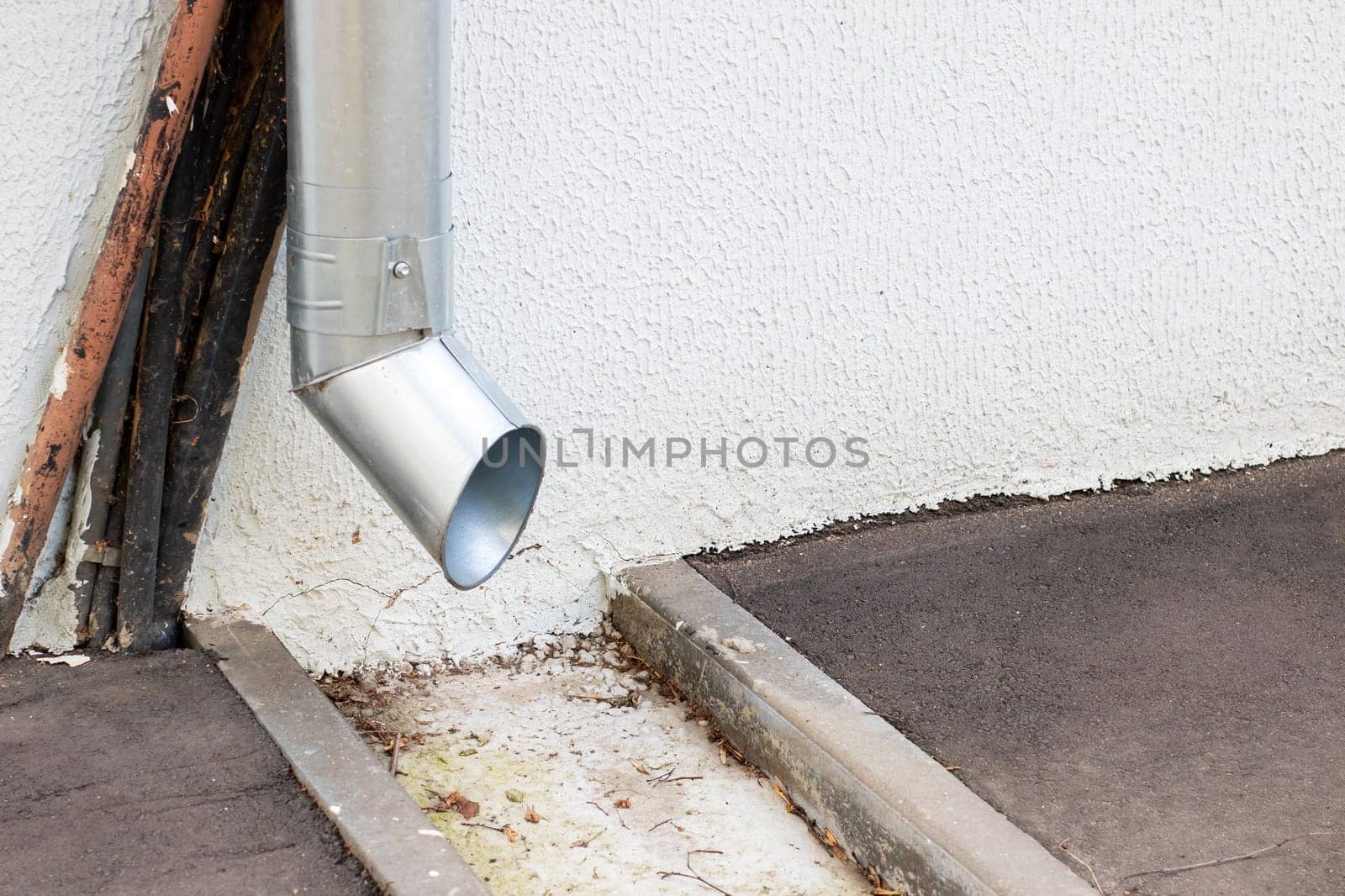 A sturdy metal pipe is currently hanging off the edge of a tall building, potentially serving various functions like plumbing and drainage