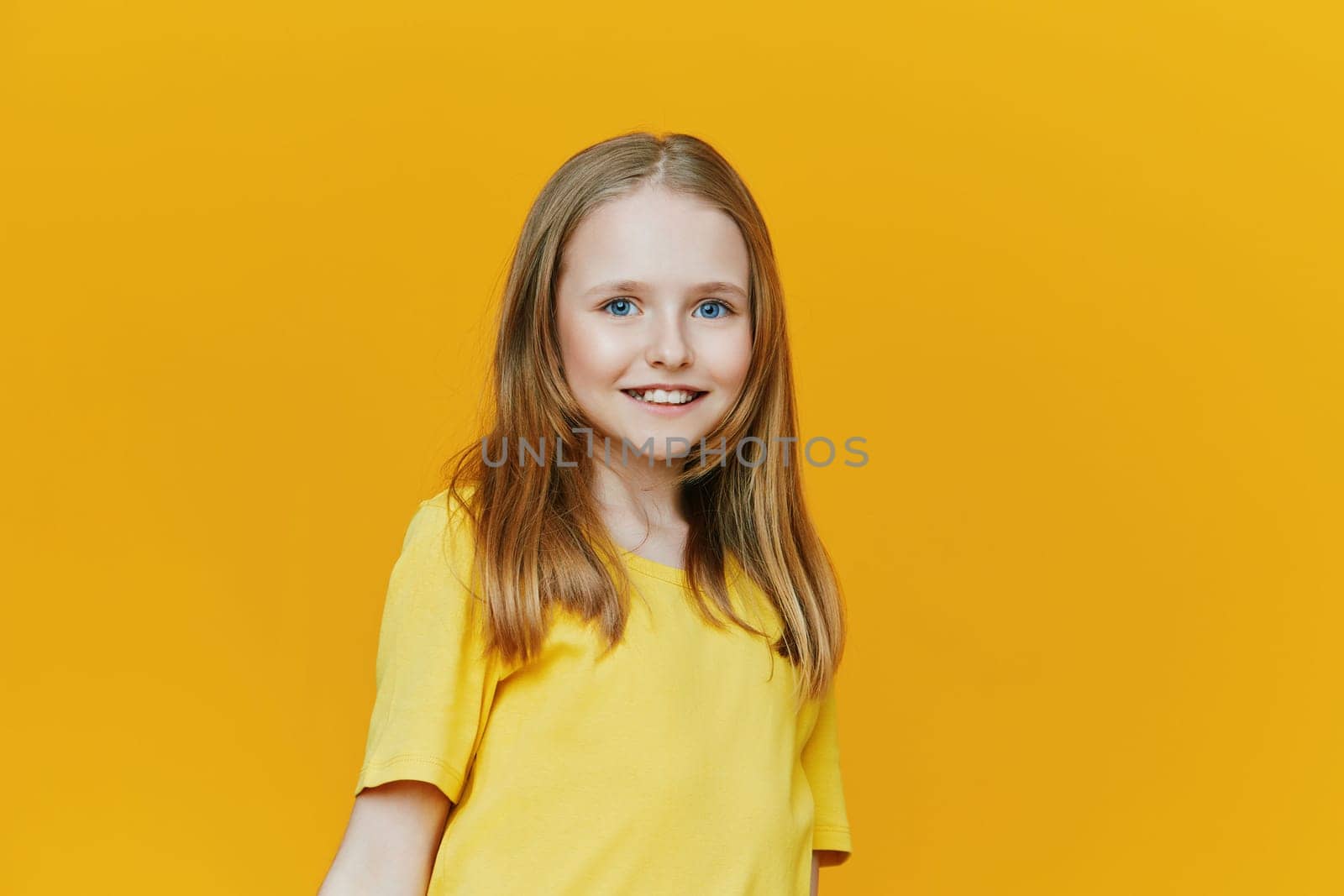 Bright and joyful young girl in a yellow shirt, exuding happiness and positivity in front of a warm yellow background, ideal for seasonal and motivational content