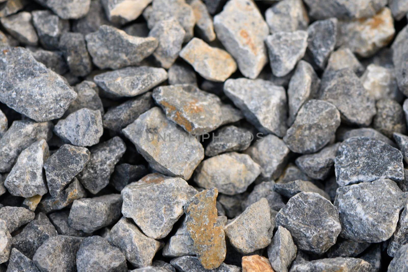 Smooth and rugged stones lay scattered together, showcasing an array of colors and textures. This collection of rocks can serve as an essential material for construction or garden design.