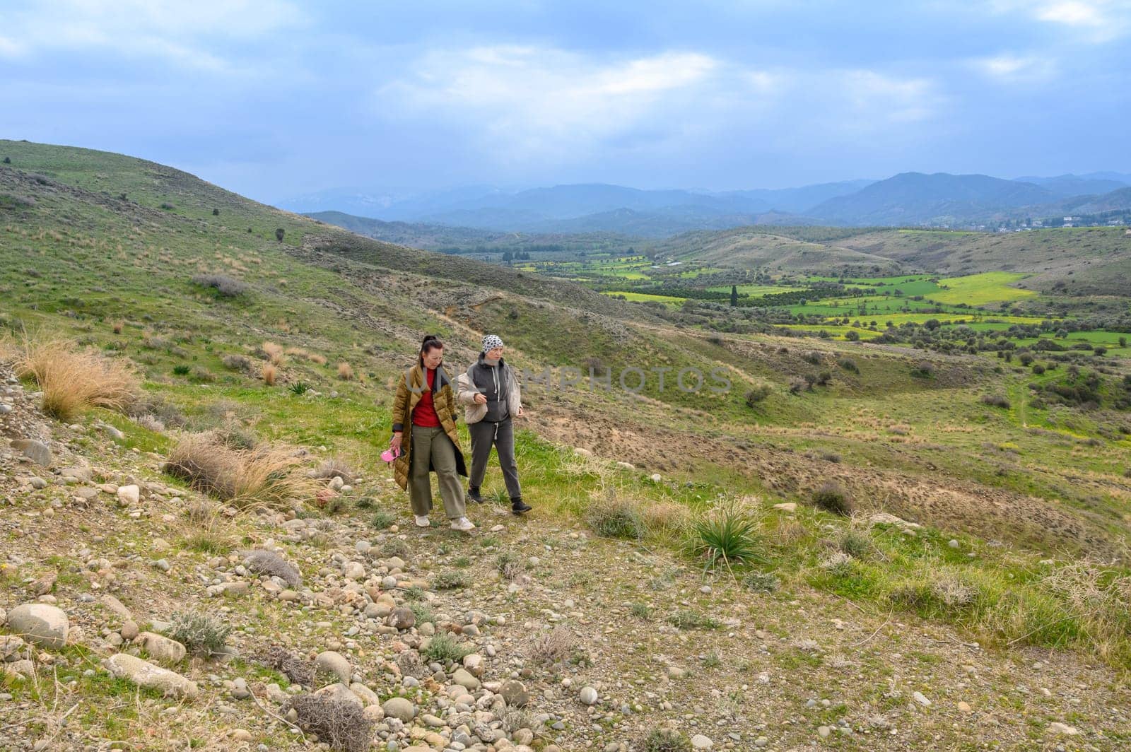 Two friends embark on a leisurely hike through lush hills, enjoying the breathtaking views and the tranquility of nature. The vibrant greenery around them invites exploration.