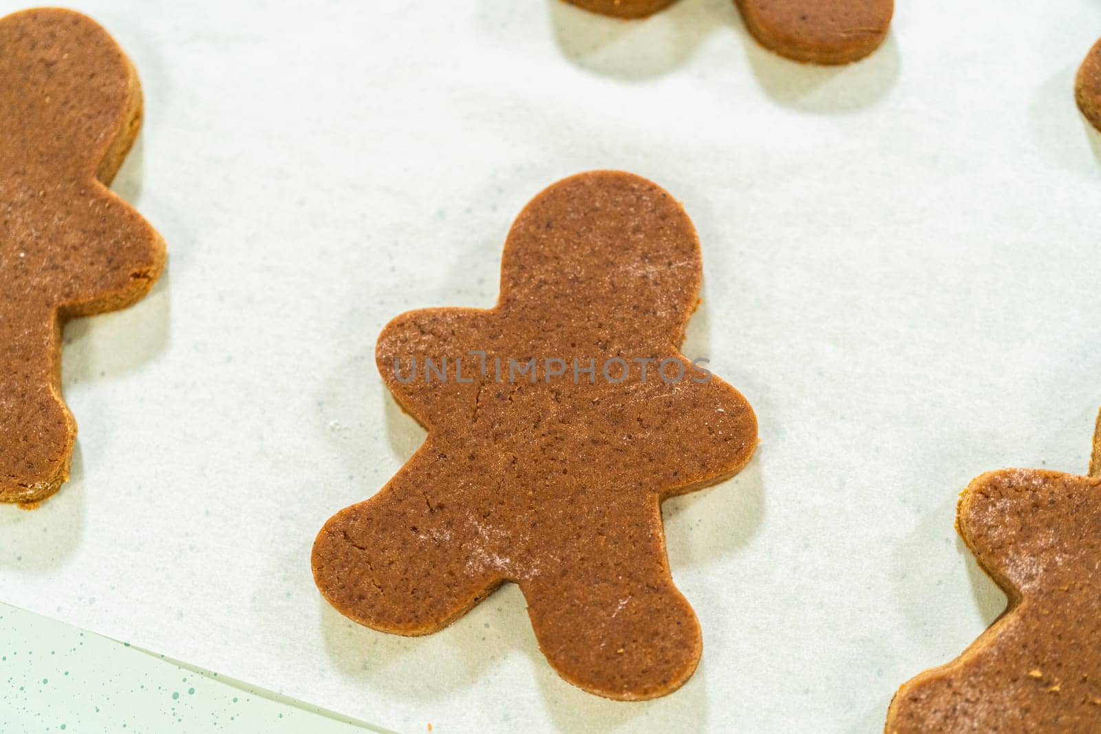 Close-up view of a single gingerbread man cookie on parchment paper, highlighting its festive design and baked finish.