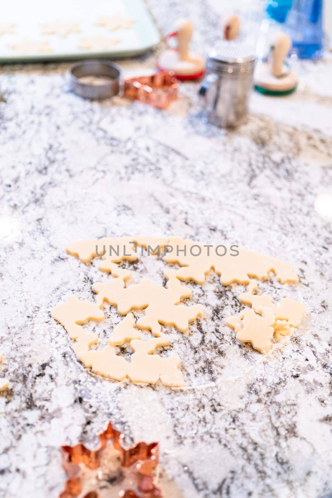 Enjoy the festive tradition of rolling out cookie dough and cutting snowflake-shaped sugar cookies, perfect for the holiday season.