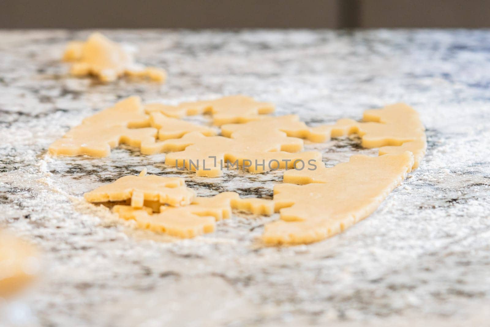 Enjoy the festive tradition of rolling out cookie dough and cutting snowflake-shaped sugar cookies, perfect for the holiday season.